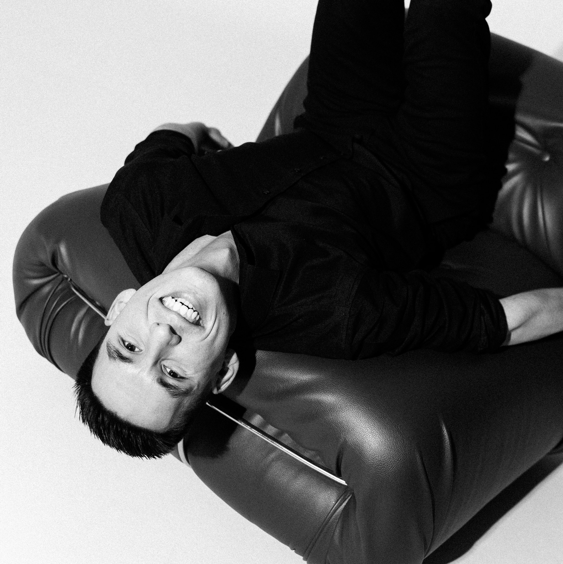 Фотограф Юра Порфирьев улыбается на кресле под жестким светом в фотостудии спб