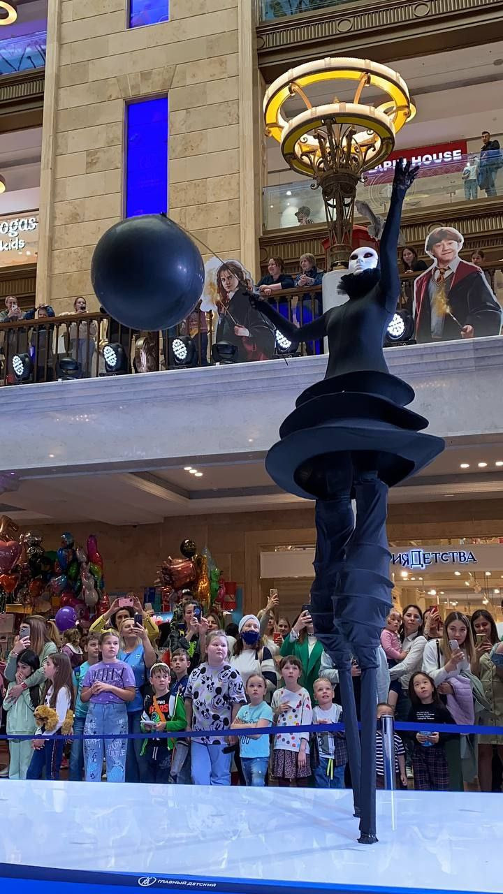 Чёрный ходулист поднимает руки наверх.