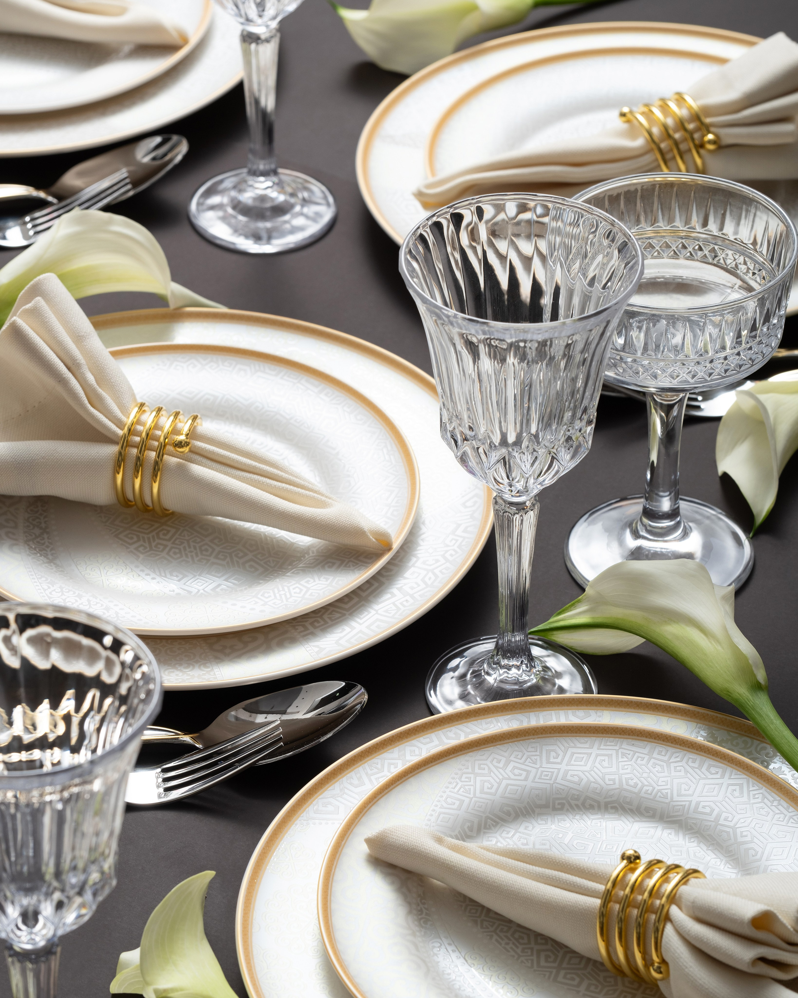 Сервировка в золотых тонах на фиолетовом фоне с бокалами и лилиями