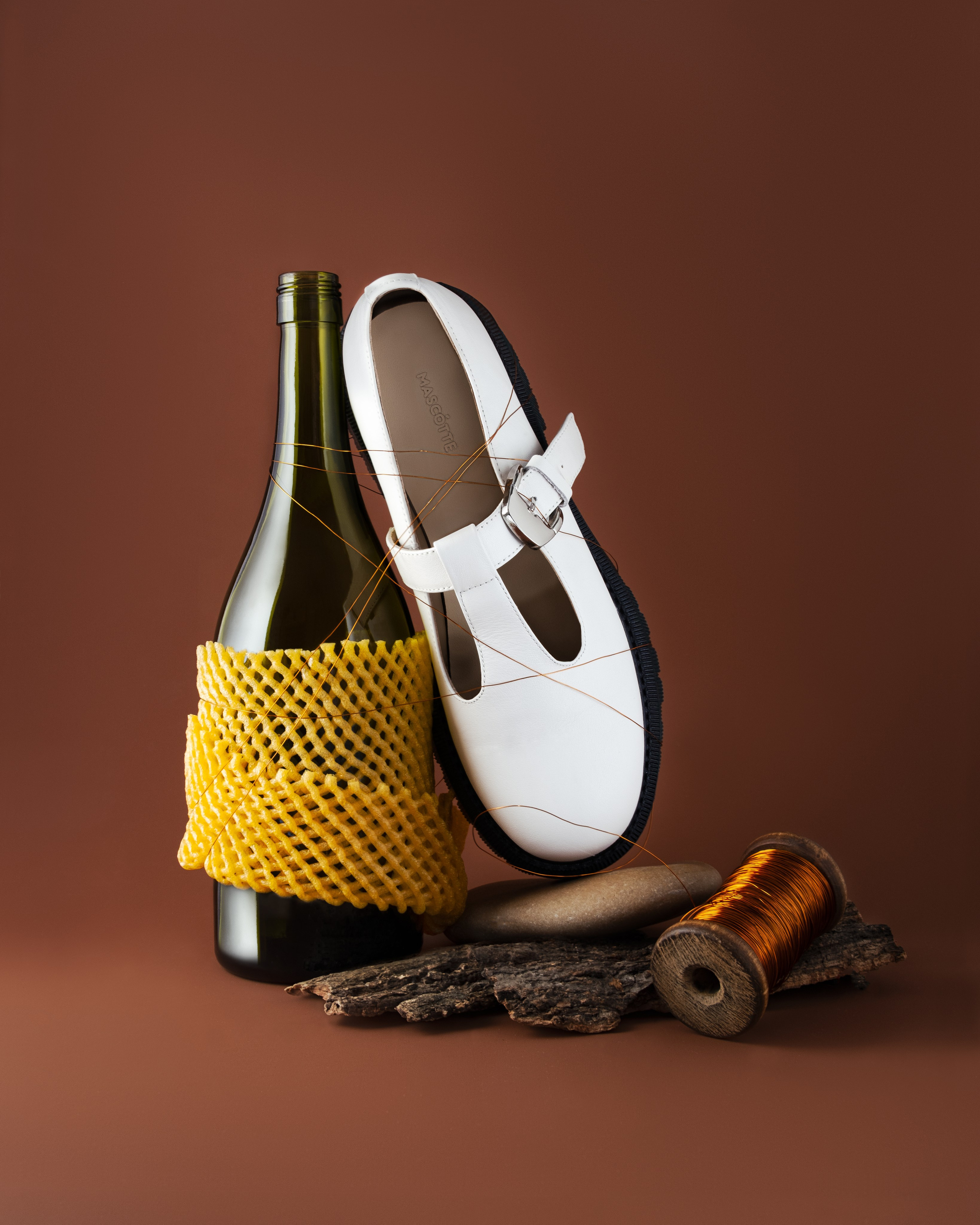 Необычная композиция на коричневом фоне с туфлёй и бутылкой из под вина
