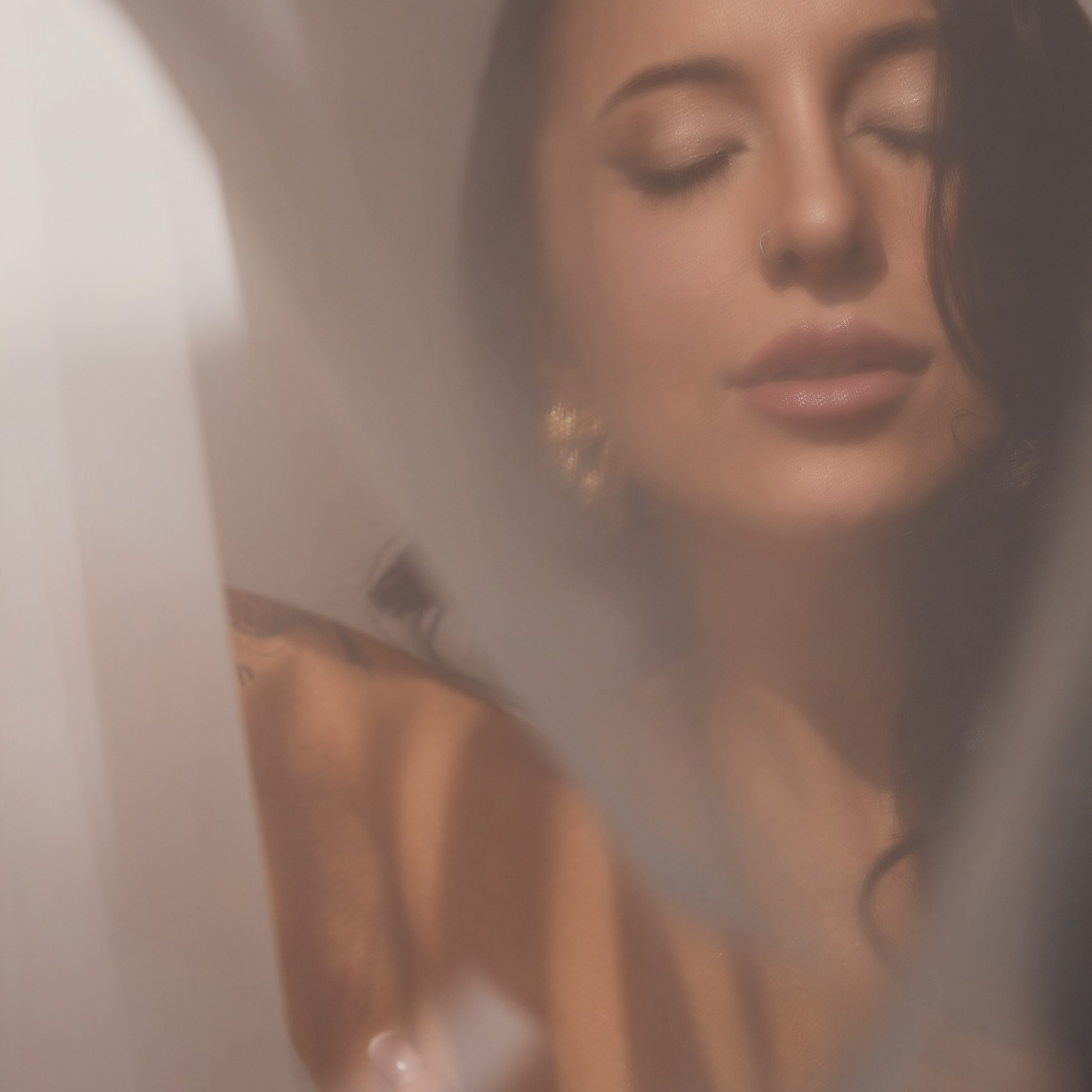 Студийная фотография: блондинка в красном облегающем платье и белых босоножках позирует на сером фоне с бликами света.