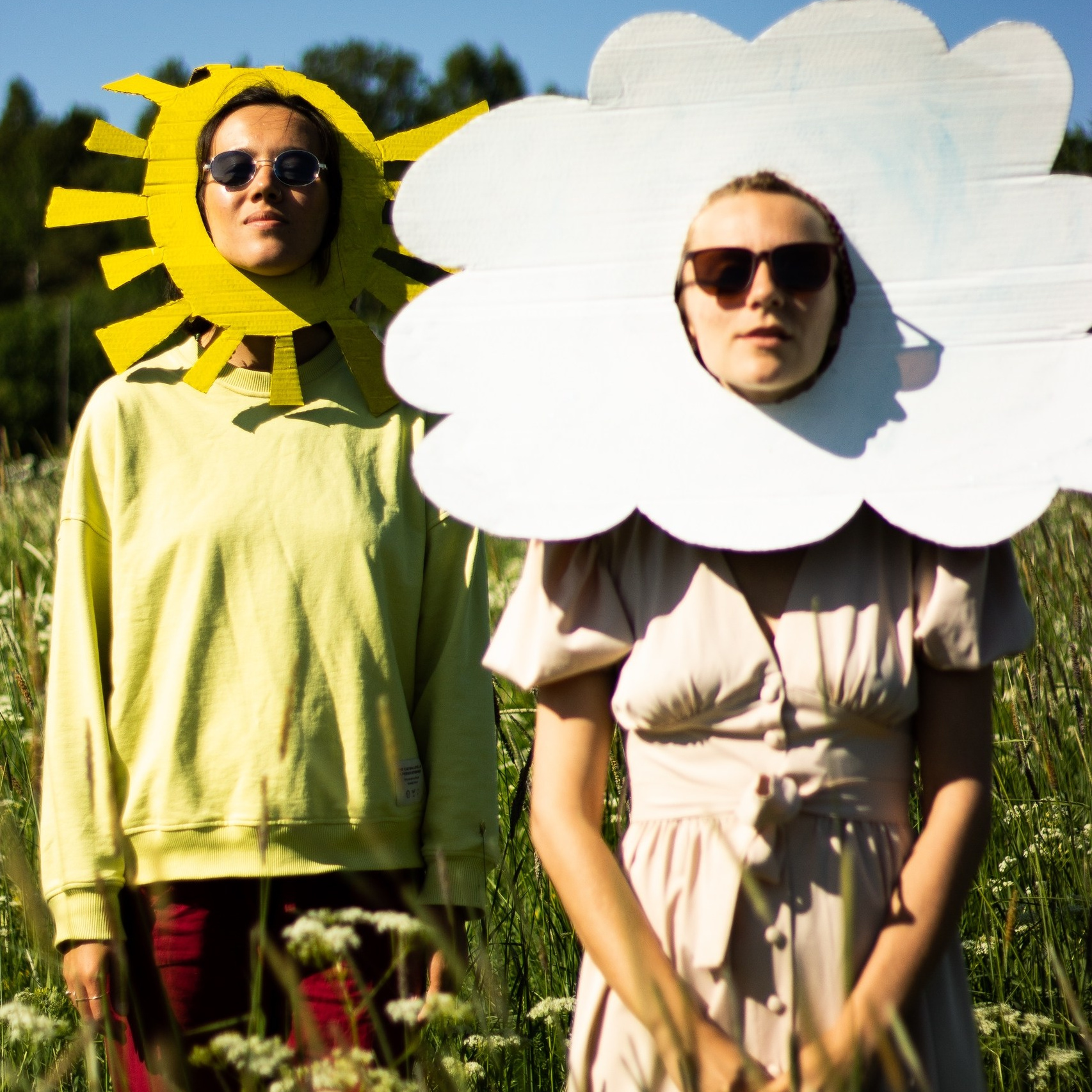 Девушки в масках облака и солнца стоят в поле в Карелии