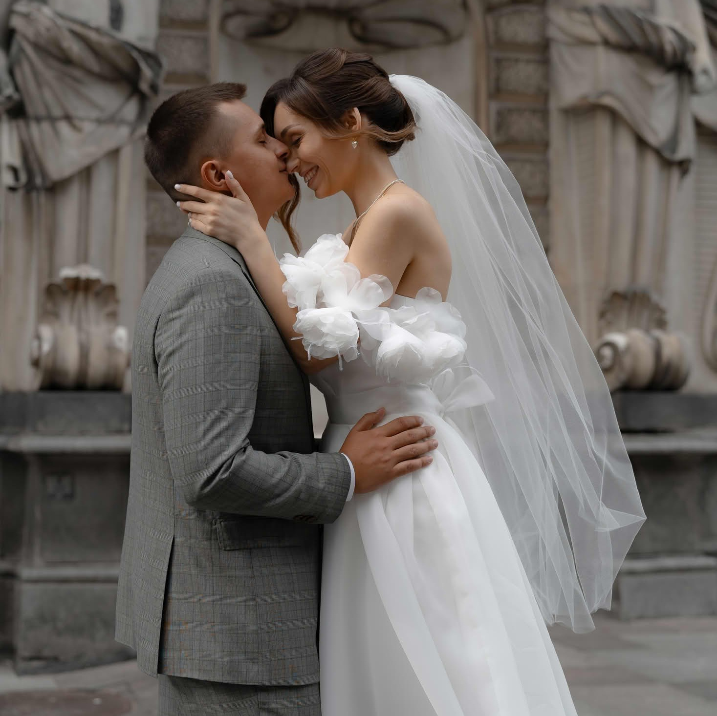 Поцелуй жениха и невесты на фоне архитектурного фасада в центре Петербурга