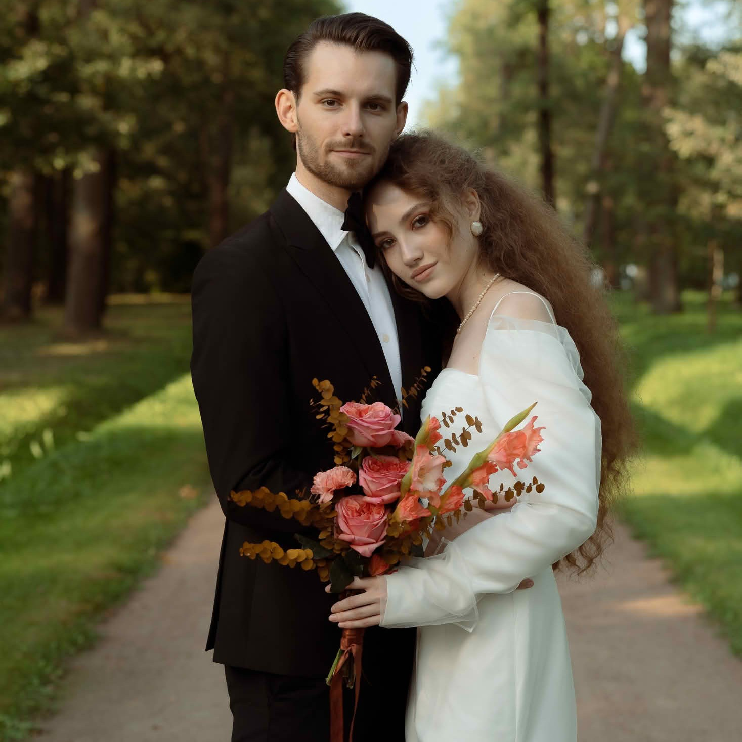 Пара на прогулке в зелёном парке в день свадьбы