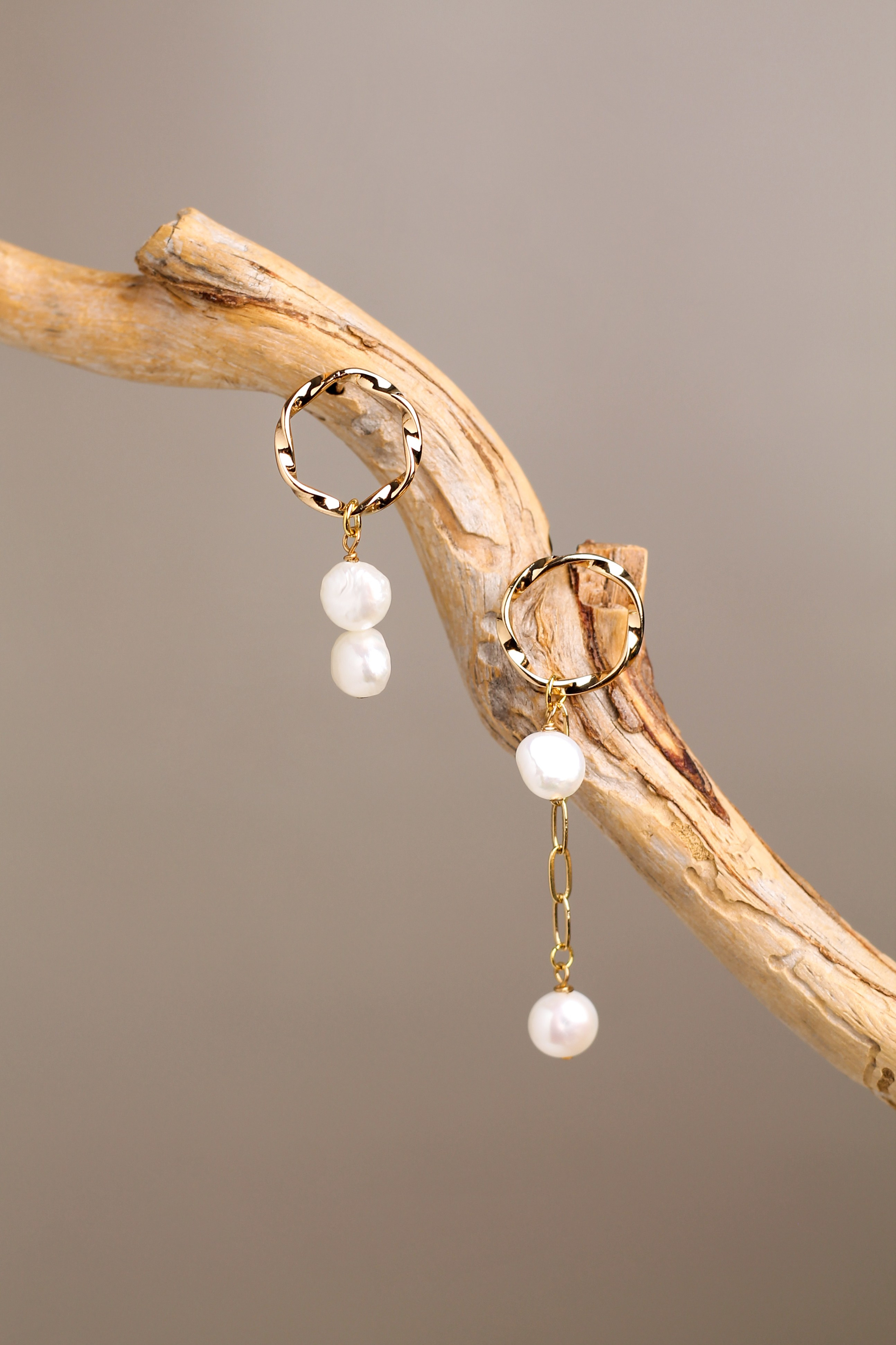 золотые сережки висят на красивой коряги на бежевом фоне. Предметный фотограф в городе Барнаул