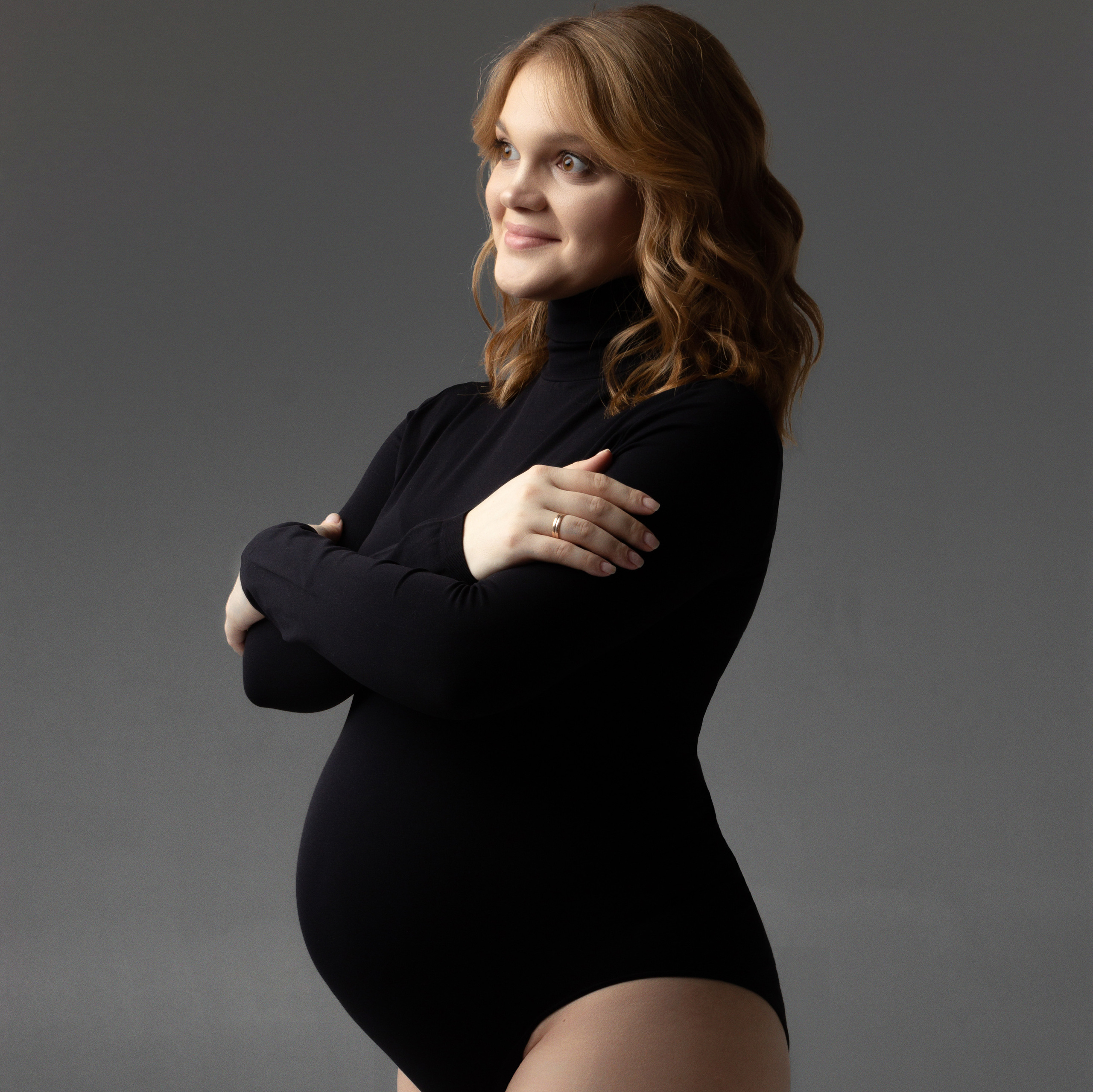 беременная девушка в черном боди сложила руки на груди