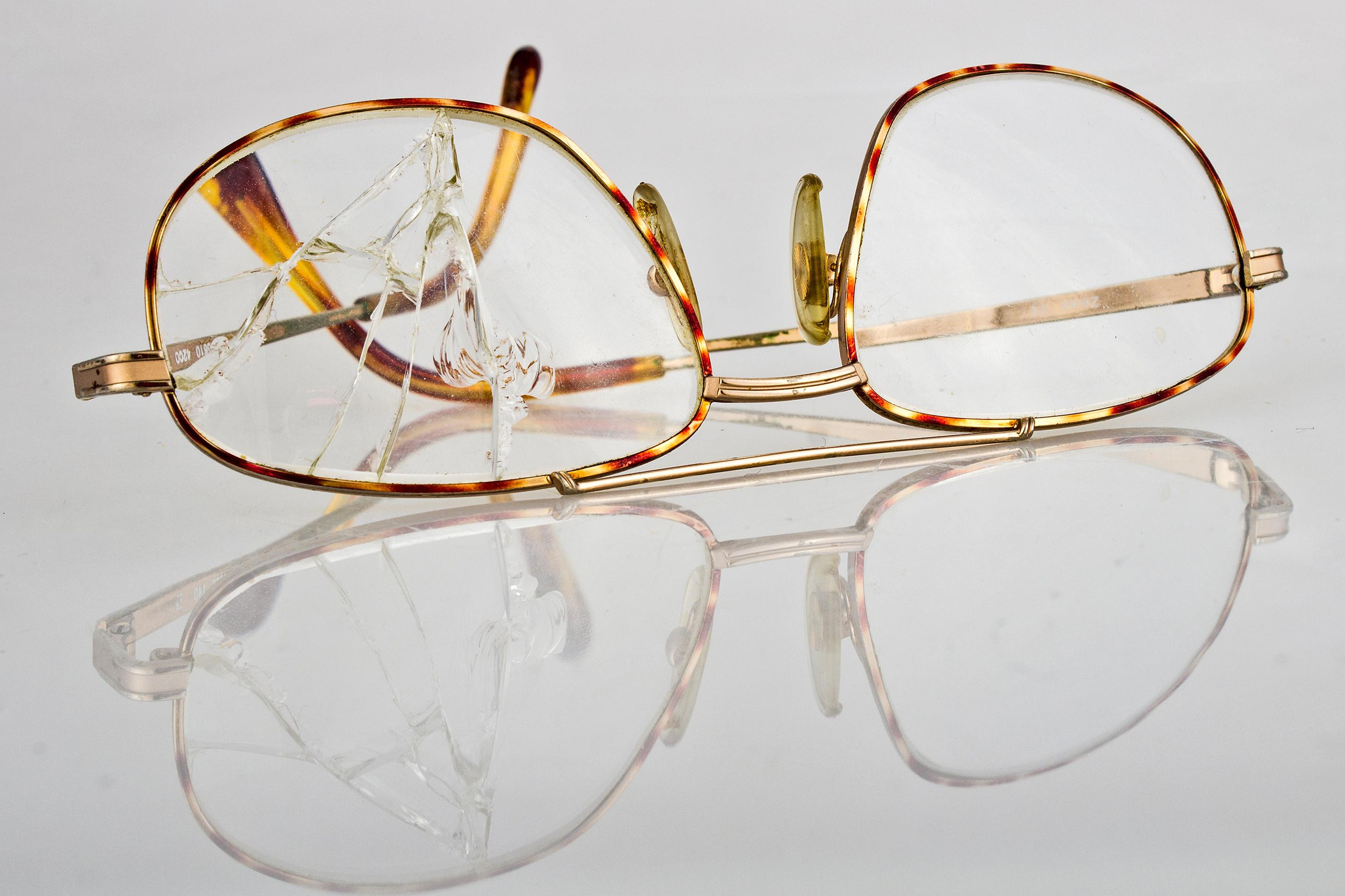 очки с треснувшим стеклом на белом отражающем фоне