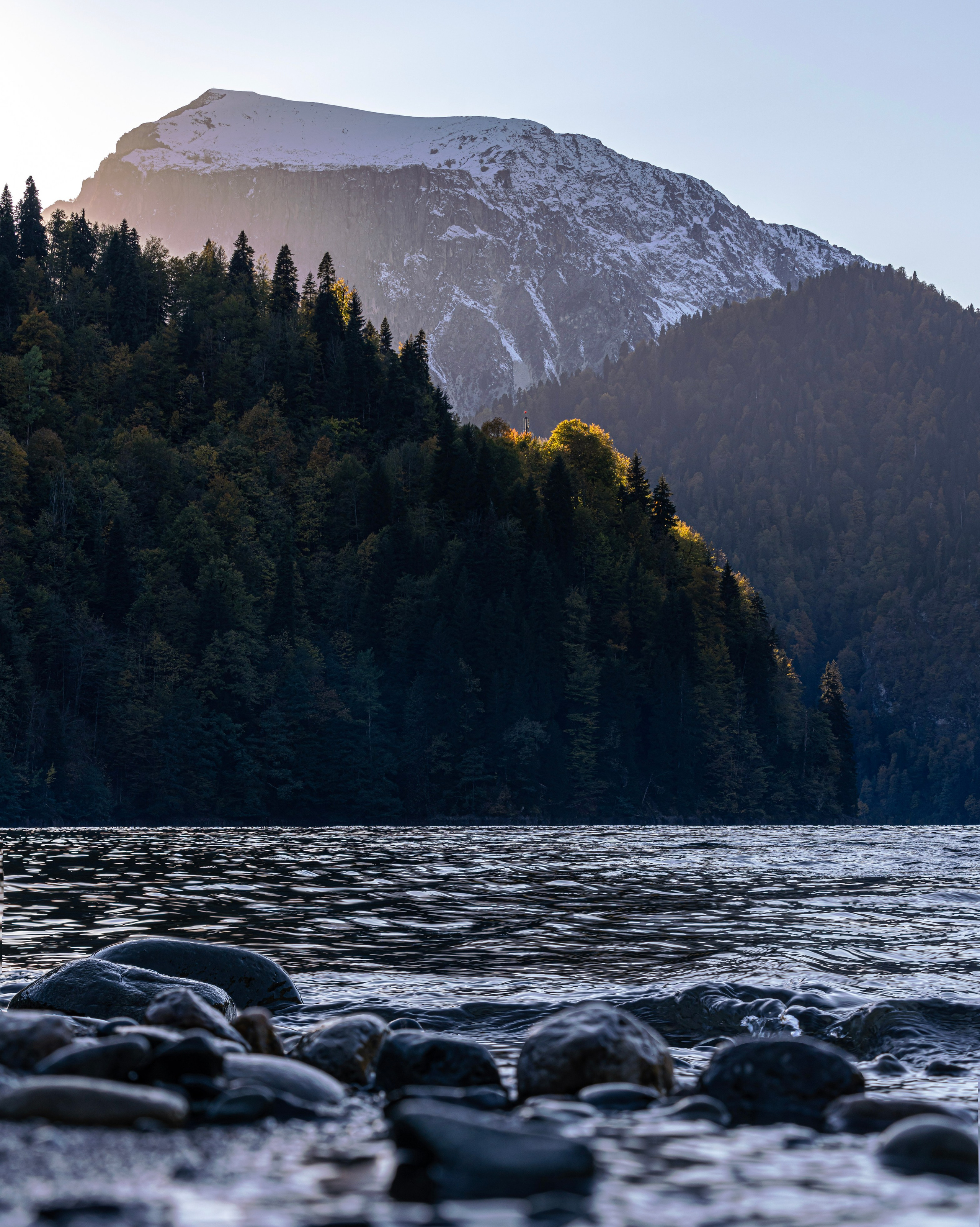 Извилистая дорога, окружённая густым хвойным лесом, ведёт к высокому горному пику на горизонте. На небе видны звёзды, подчёркивающие вечернюю атмосферу