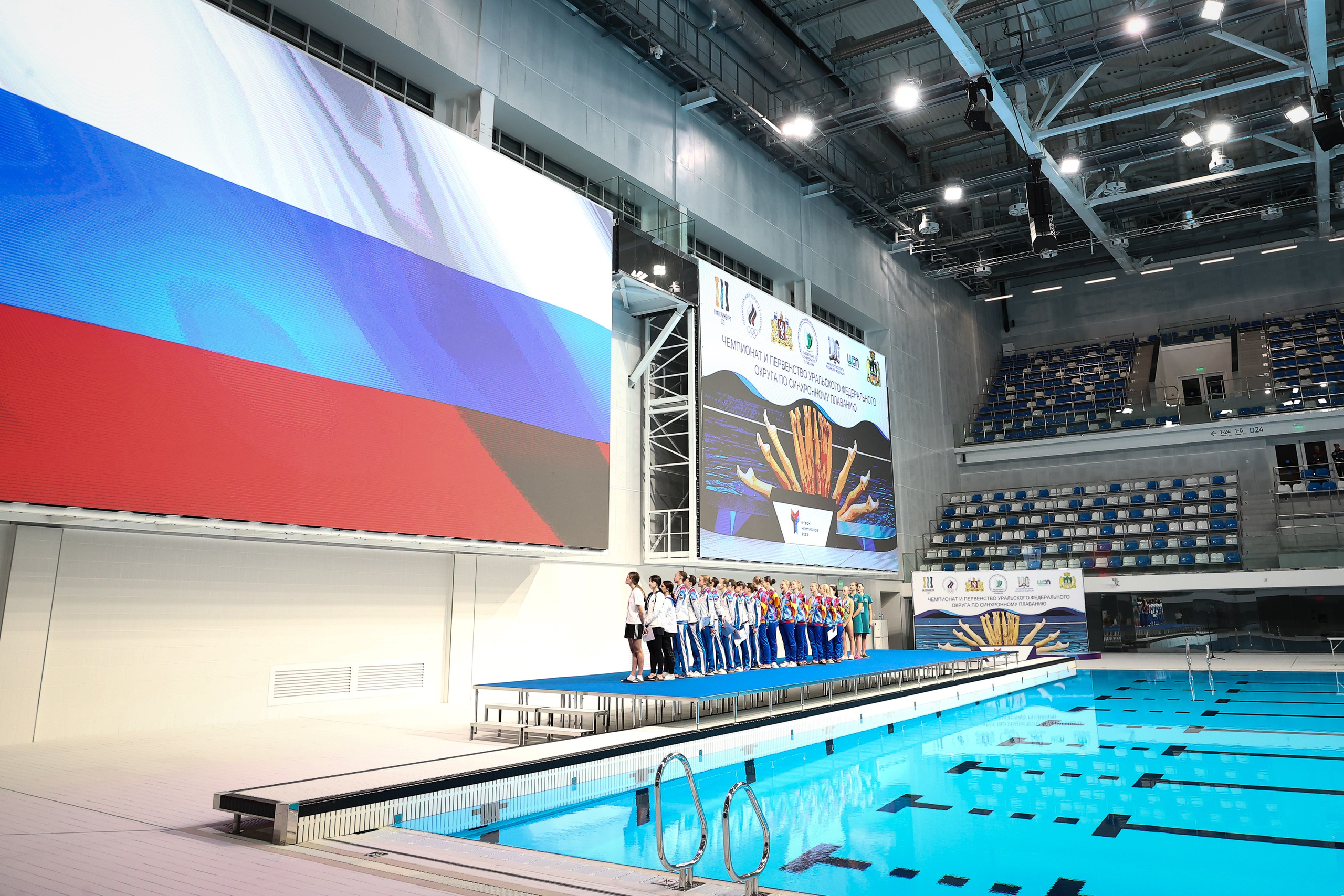 Спортсмены поют гимн и смотрят на Флаг Российской Федерации на Чемпионате и Первенстве УРФО по синхронному плаванию