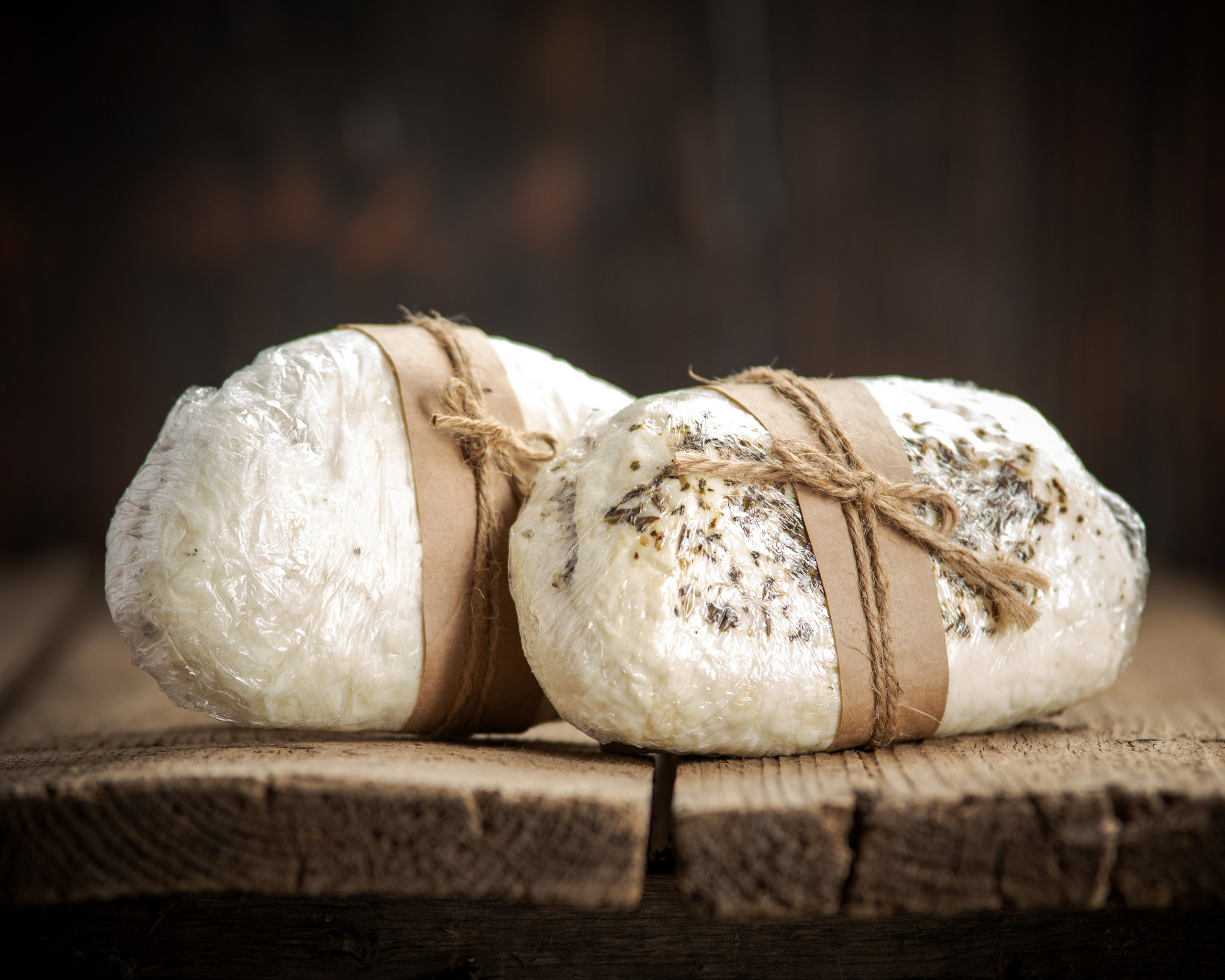 Головка сыра халлуми с мятой, упакованная в пищевую пленку.