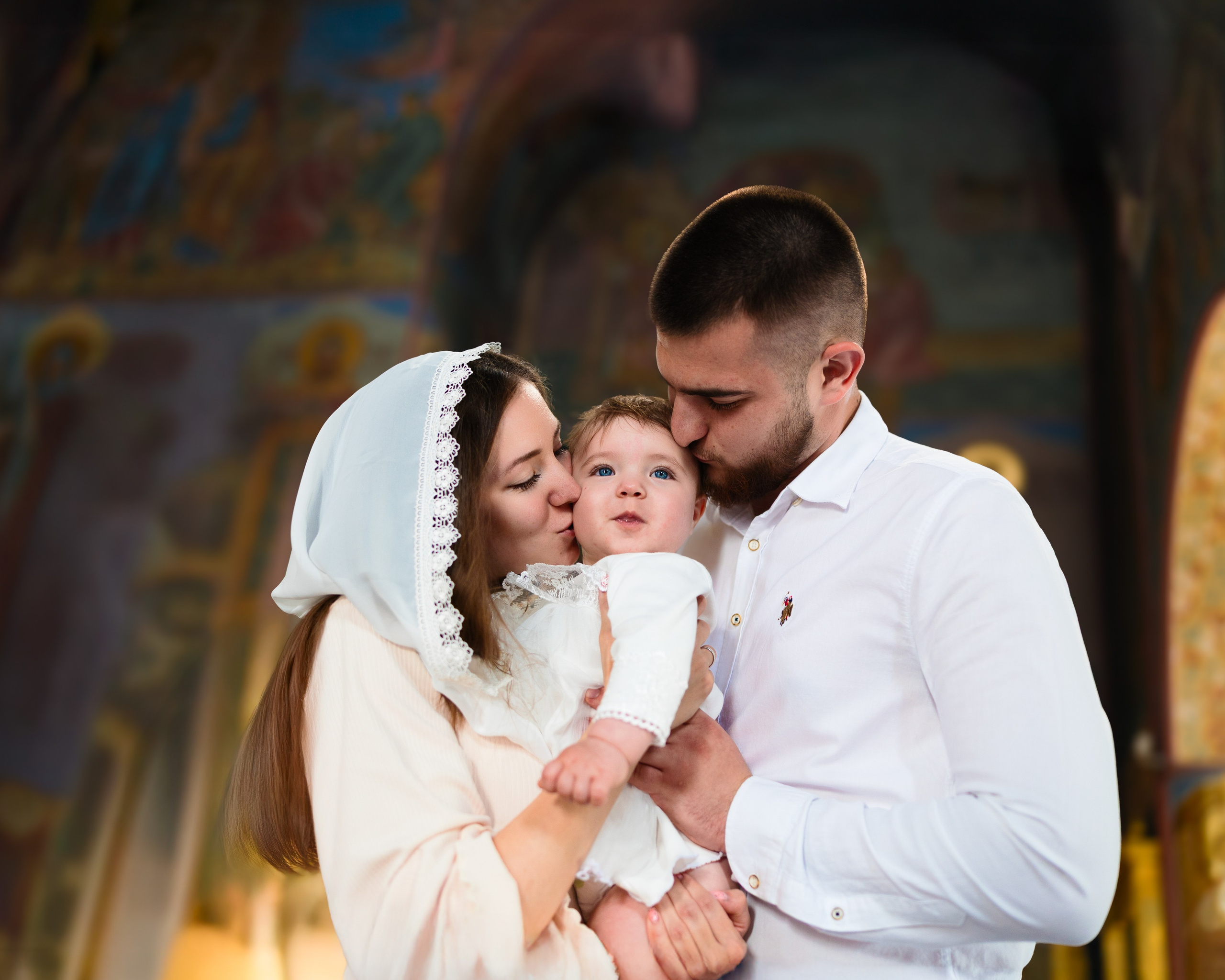Счастливые родители после крещения малыша делают совместное фото