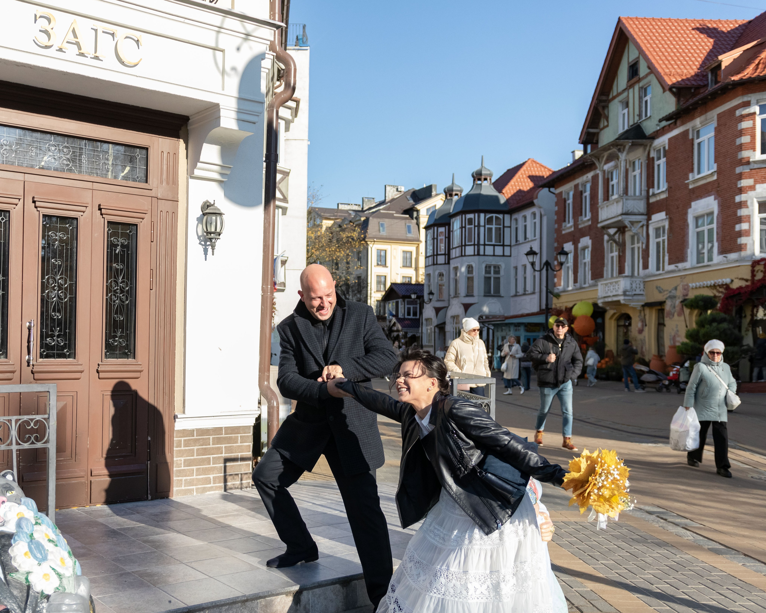 молодая супружеская пара с букетом заходит в загс
