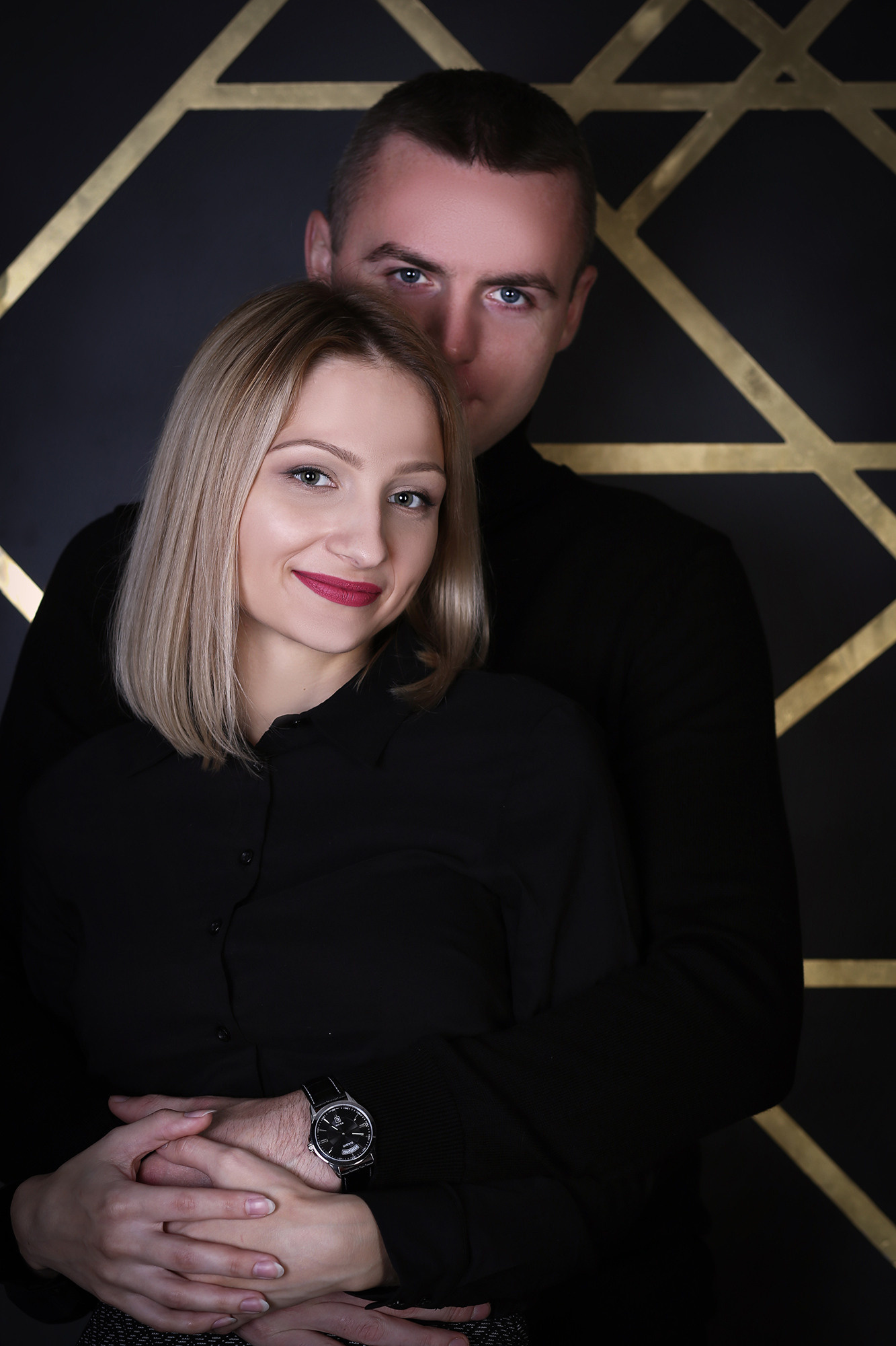 парень в черном обнимает девушку в черном на черном фоне