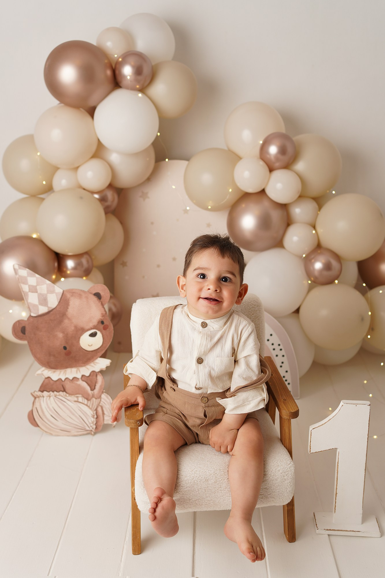 На фото малыш сидит на стульчике на праздновании своего первого года.