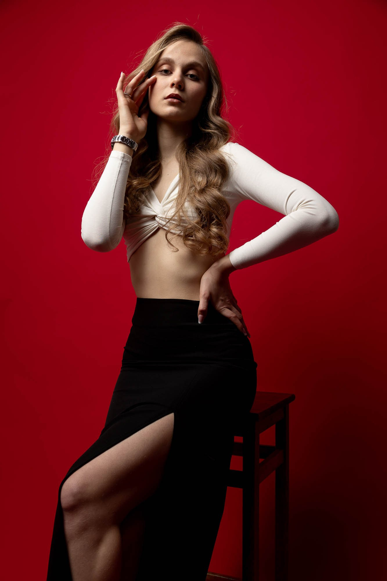 Модель в черном платье позирует на красном фоне — пленочная фотография в стиле fashion