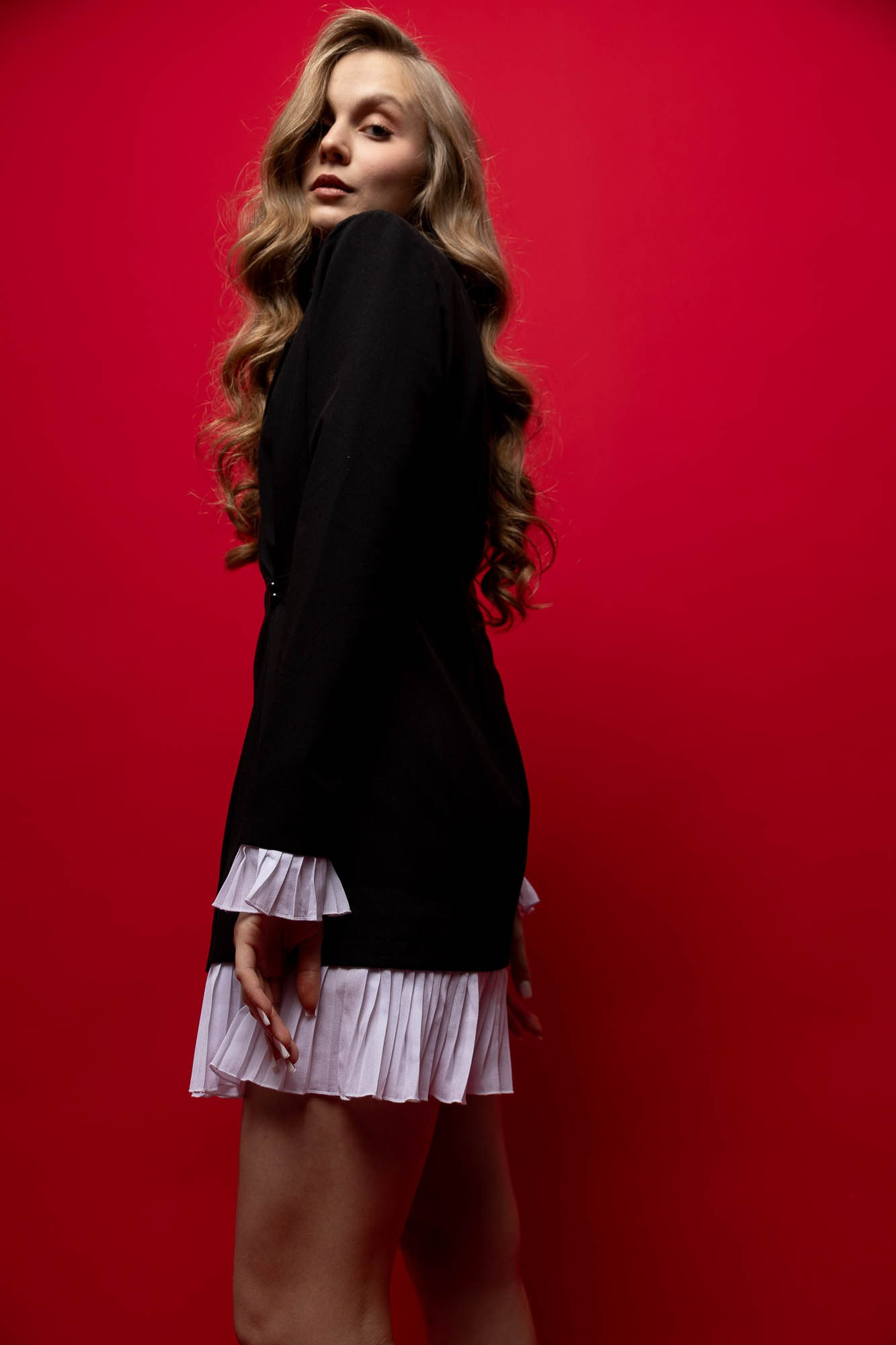 Женщина в черном наряде позирует на красном фоне — авторский художественный стиль фотографа.