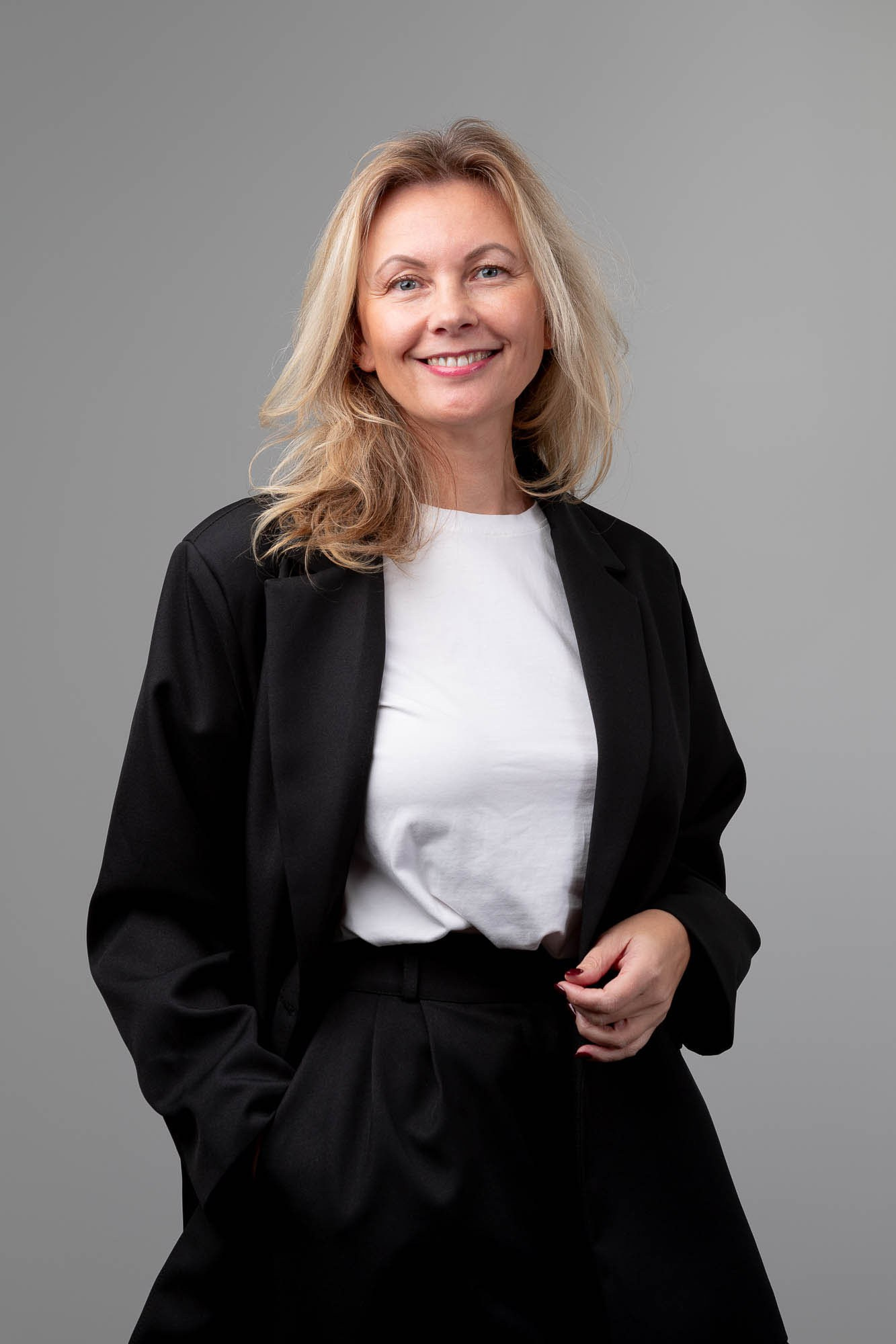 Молодая женщина в деловом образе позирует в студии — корпоративная фотосъемка для профессиональных целей.