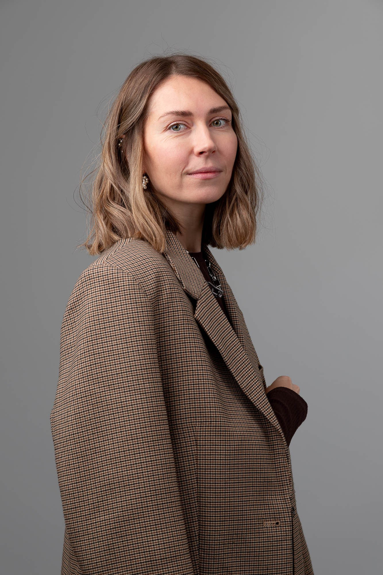 Женщина в светлом пальто на фоне, деловой профиль — бизнес-портрет для корпоративного сайта.