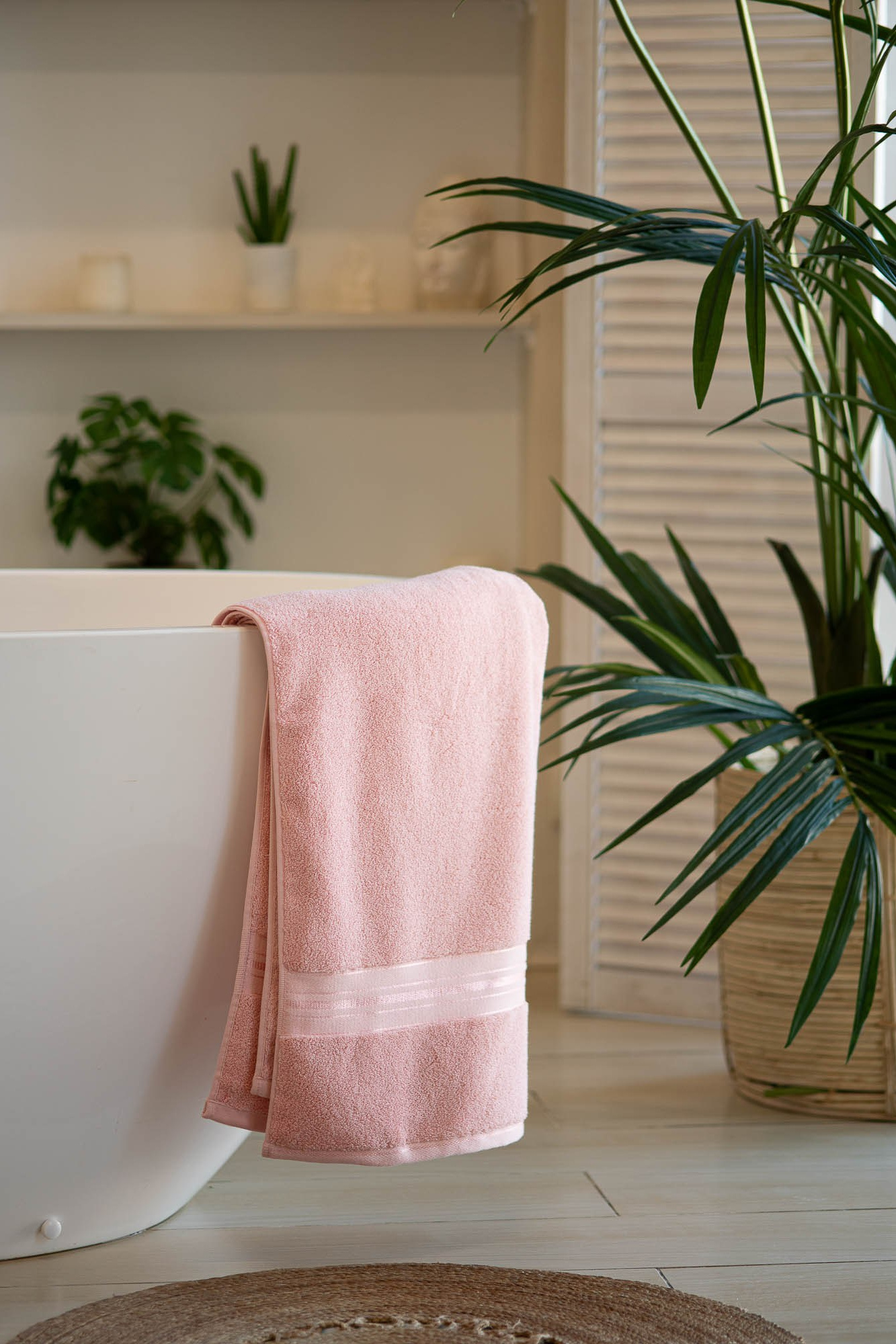 Розовое полотенце на фоне светлого интерьера с зелёным растением — создание домашнего уюта с помощью предметной фотосъемки.