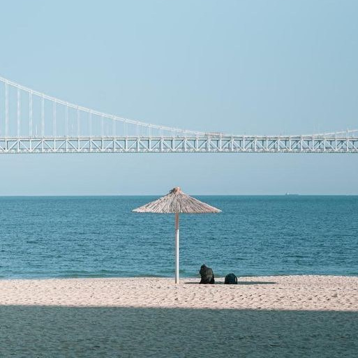 Пляжный зонтик на пляже Гвангалли на фоне моста Кванан, Пусан