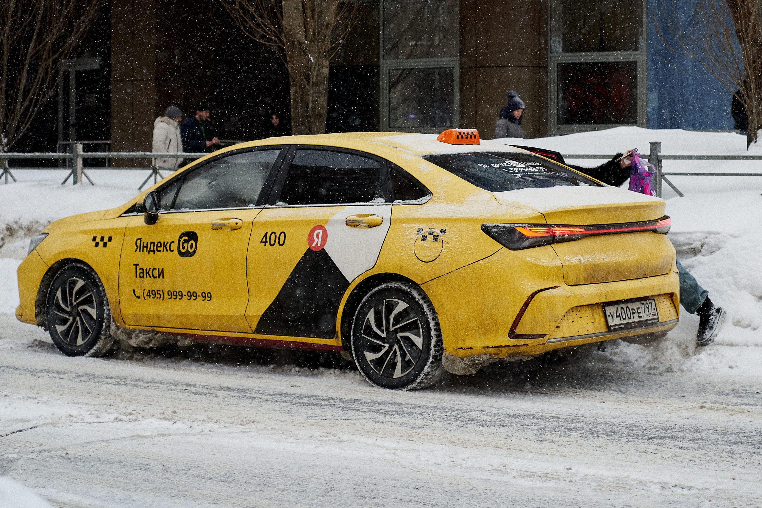 Yellow taxi in snowfall.Yellow taxi driving through snowy streets in Russia during a snowstorm. A young woman appears to have forgotten her handbag.