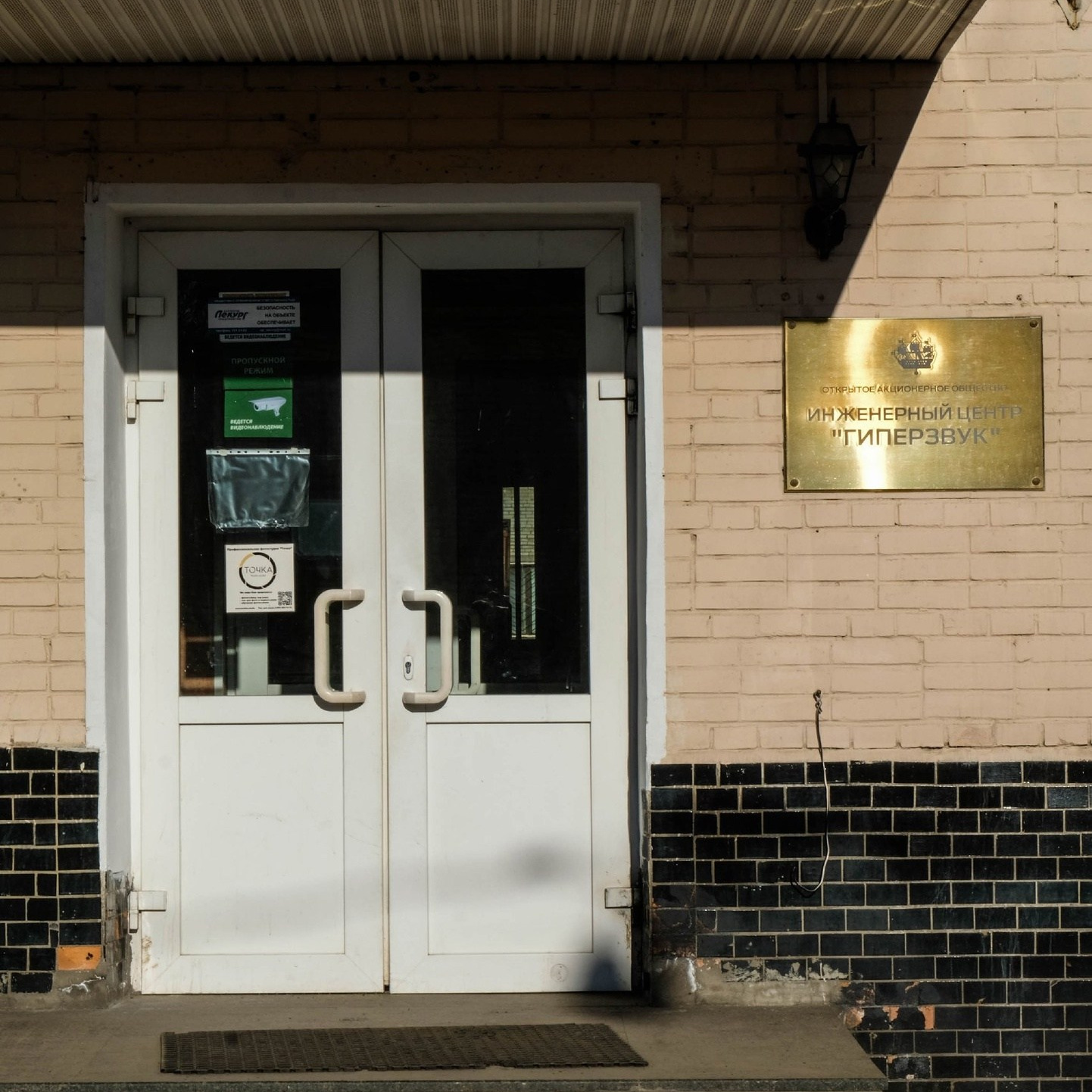 Вход через белые двери с золотой табличкой в здание Инженерного центра Гиперзвук на Крупской 55Б