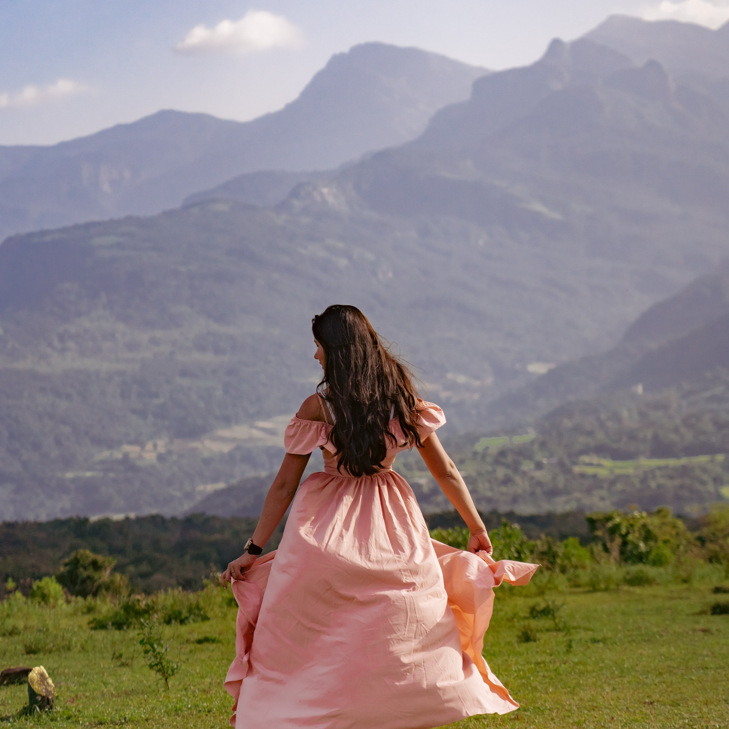 Girl in a pink dress against the backdrop of tall mountains