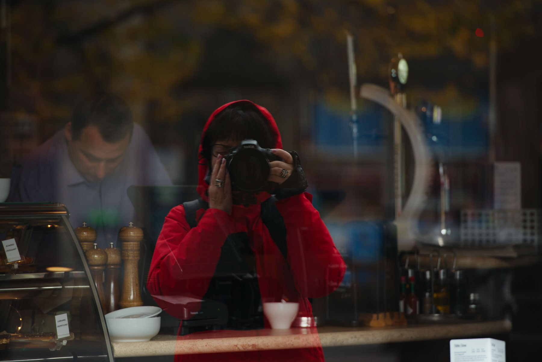 Автопортрет фотографа в красной куртке, отражение в окне кафе — уличная арт-фотография с красным акцентом | Talulla