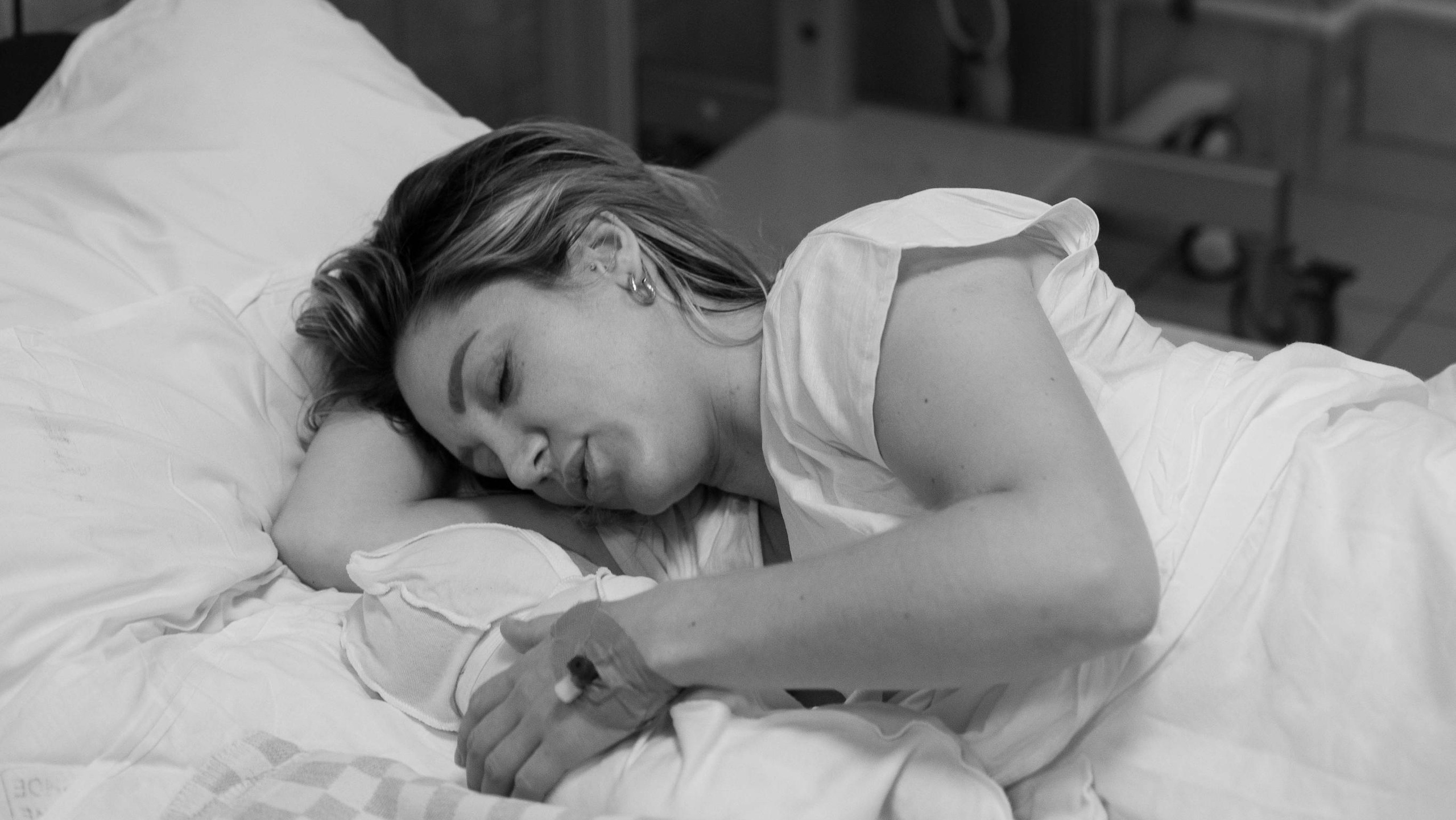 Фото родов. Мама лежит с только что родившимся малышом. Улыбается