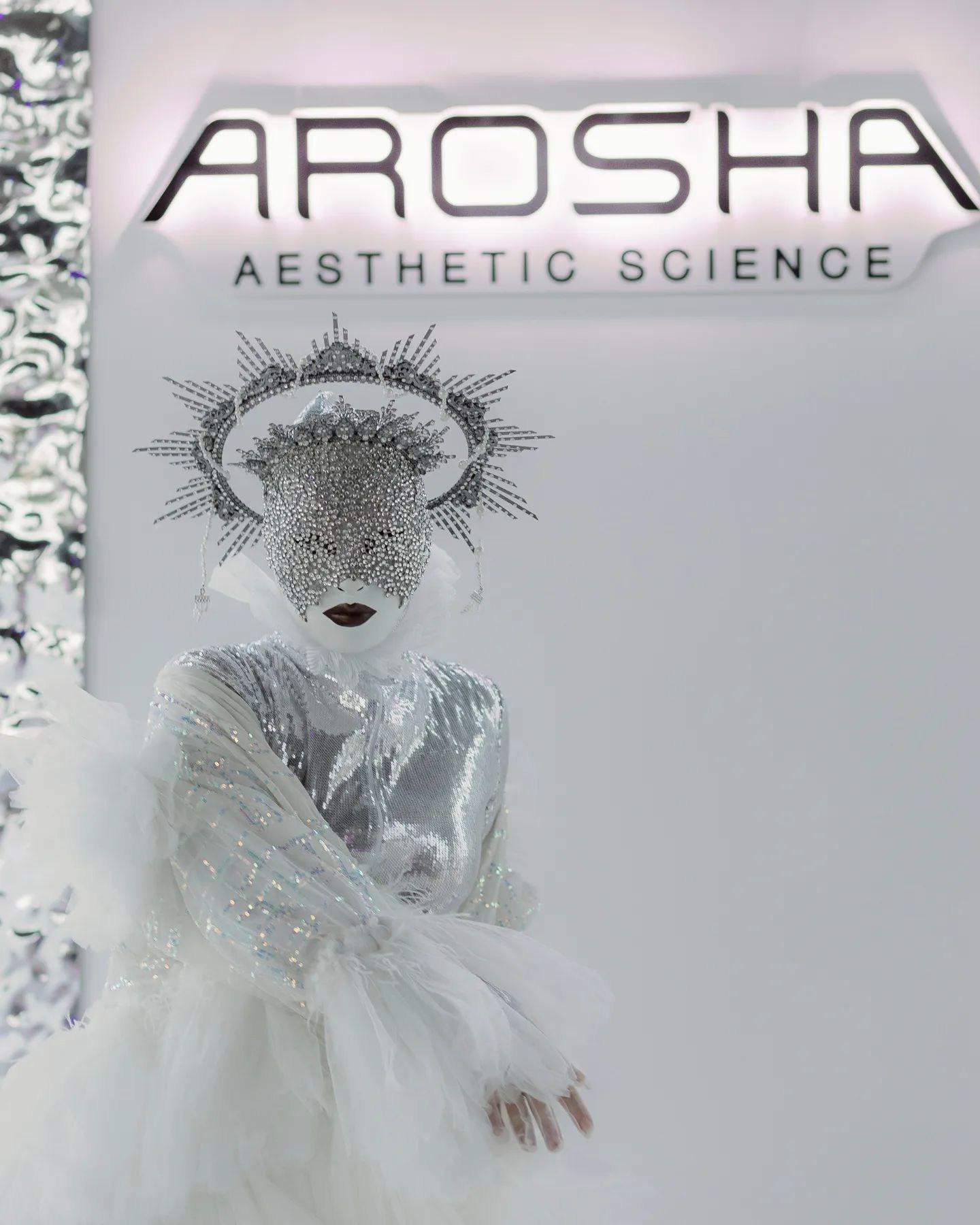 Артист с маской на лице и нимбом над головой у стенда Arosha