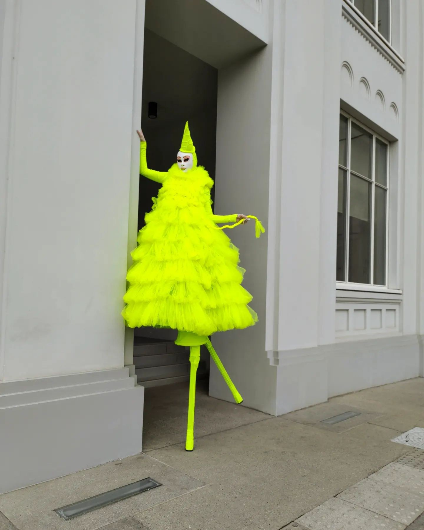 Ходулист на встрече гостей во время фотосессии у белоснежной стены