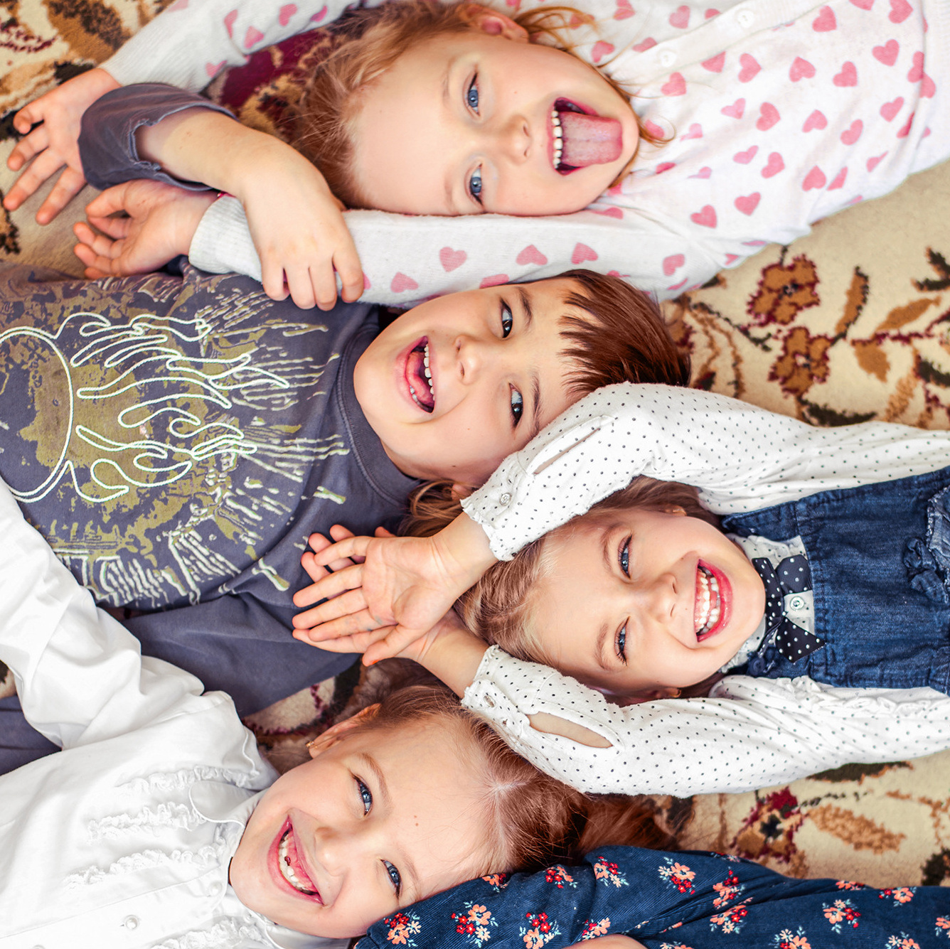 Детский групповой портрет, на котором дети лежат на полу головами друг к другу, взявшись за руки.