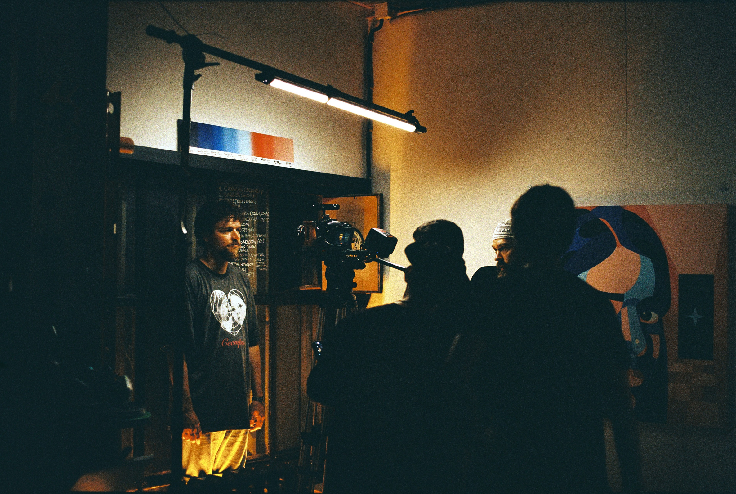 Оператор, режиссёр и техник по свету двигают штатив с кинокамерой к главному герою сцены