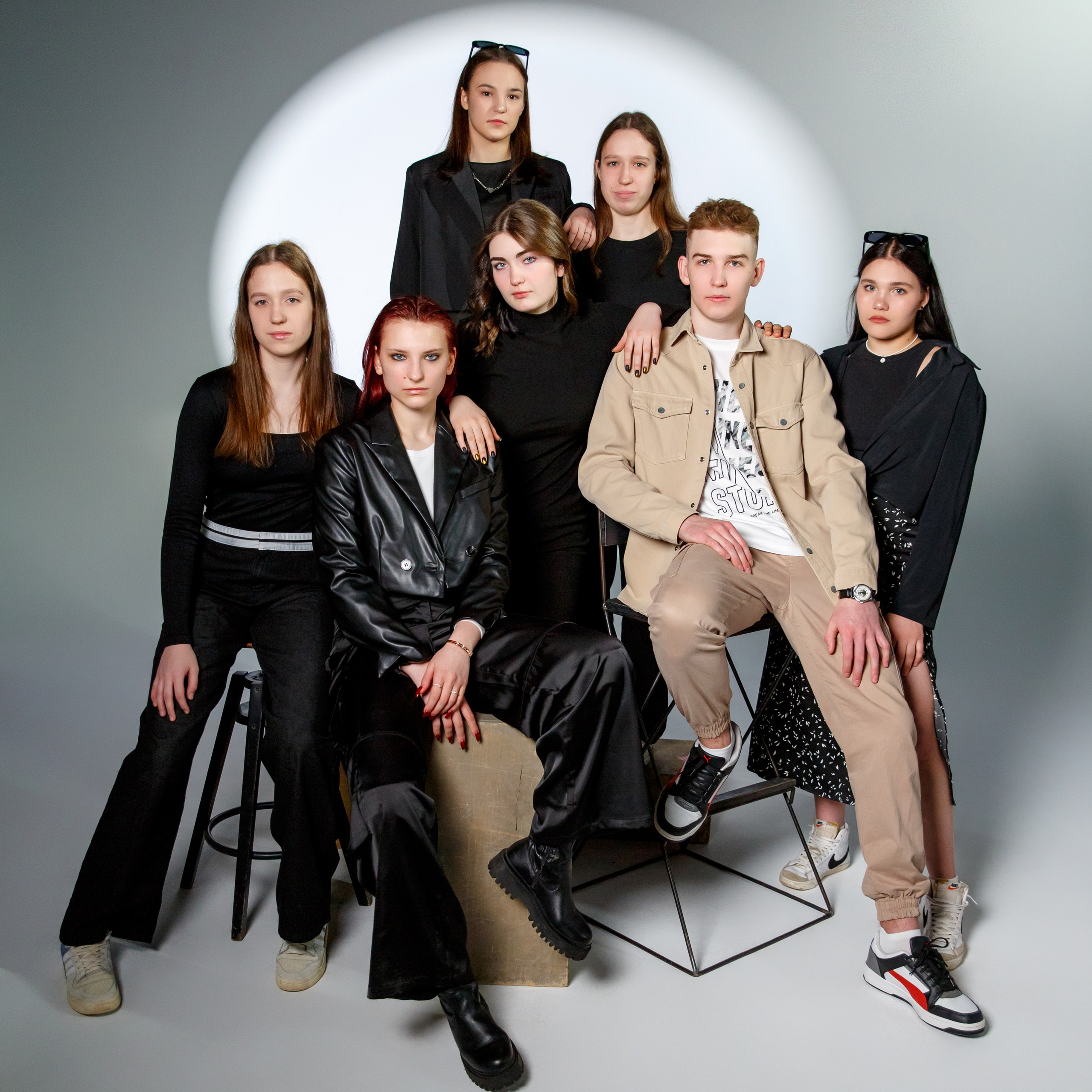 Выпускники сидят на стульях и стоят в свете прожектора на циклораме. Работа фотостудии Вышка для 11 класса.