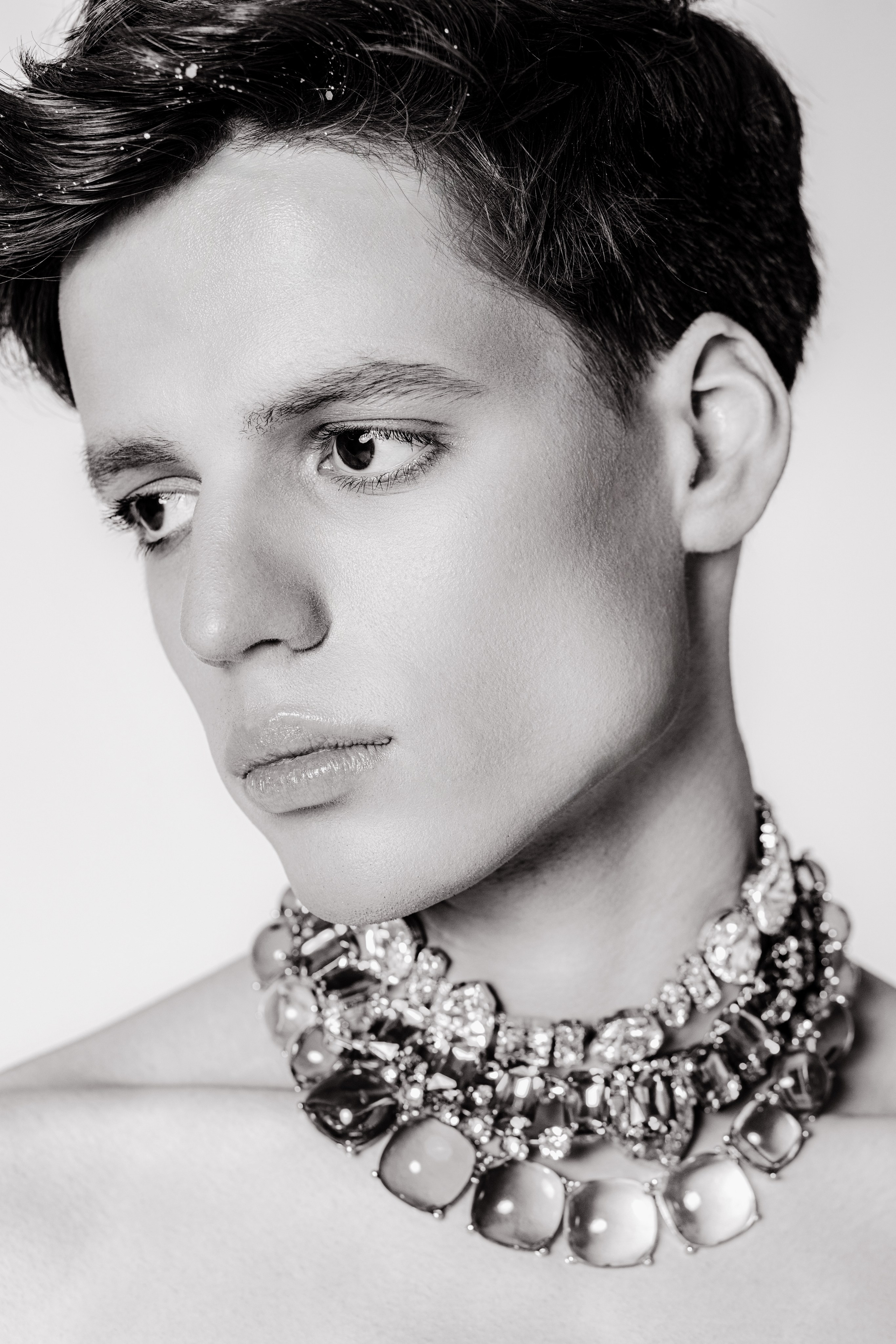Fashion-портрет: стразы на лице, взгляд в сторону от камеры с массивным колье. 