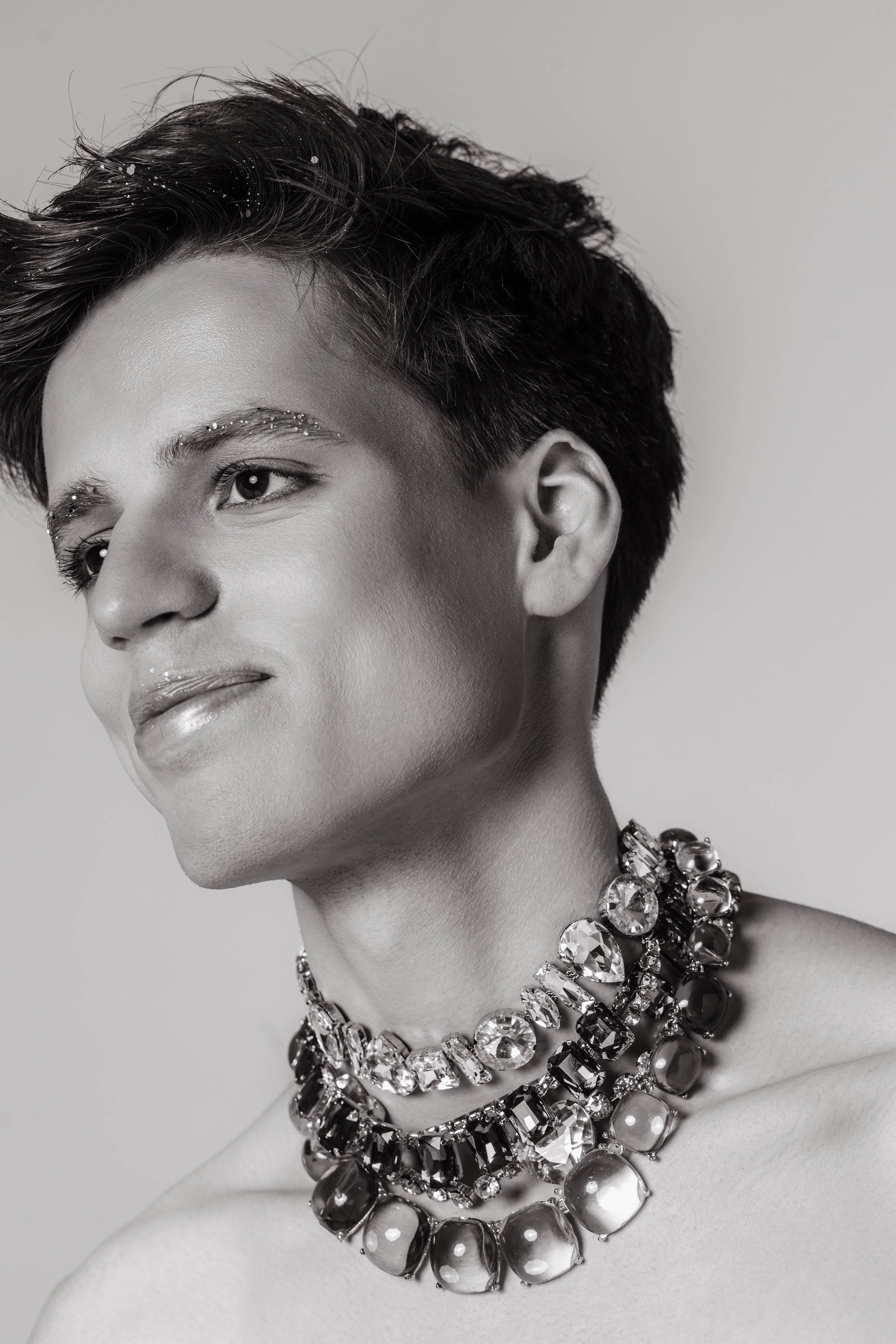Fashion-портрет: стразы на лице, взгляд в сторону от камеры с массивным колье. 