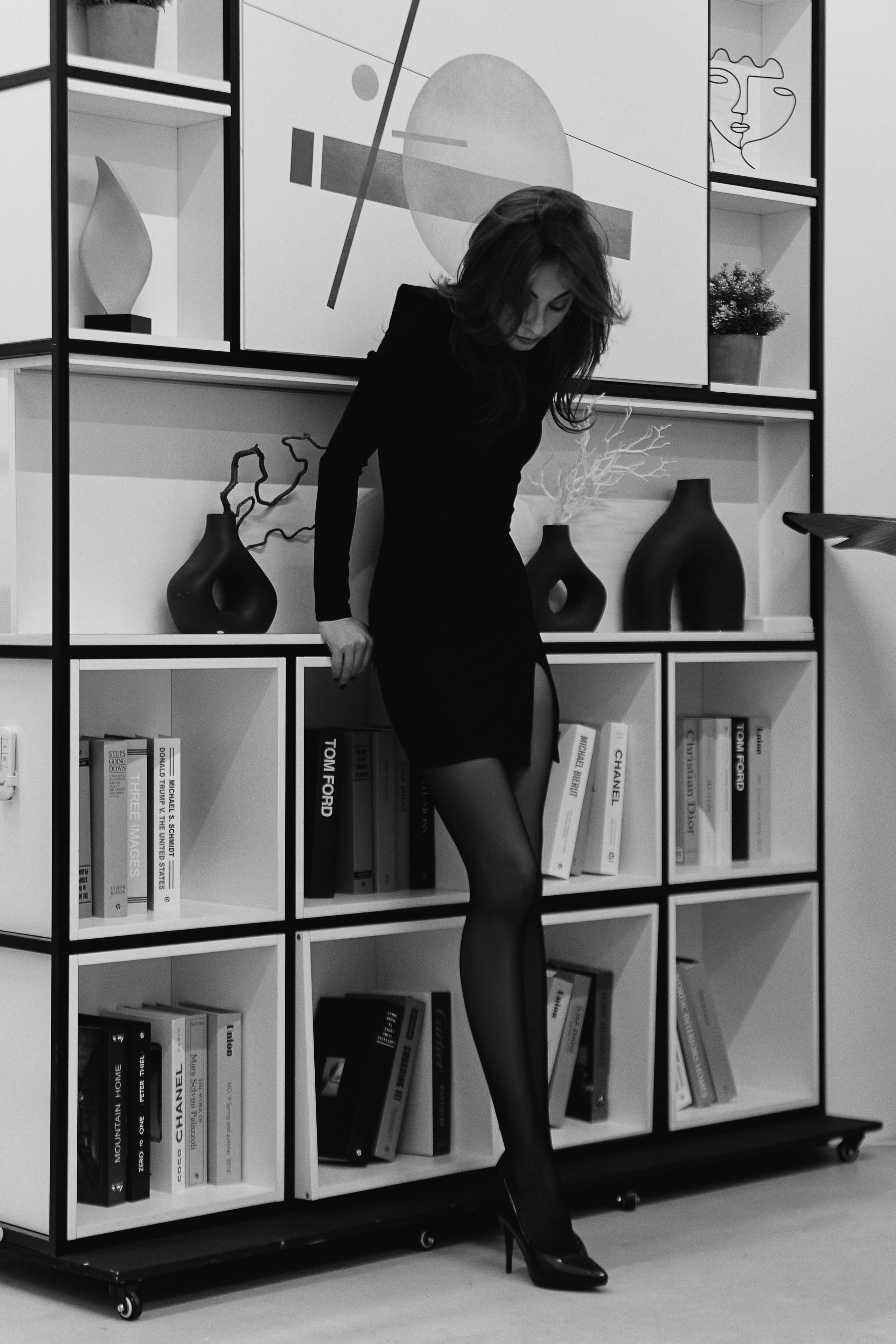 Девушка в черном обтягивающем платье на фоне книг