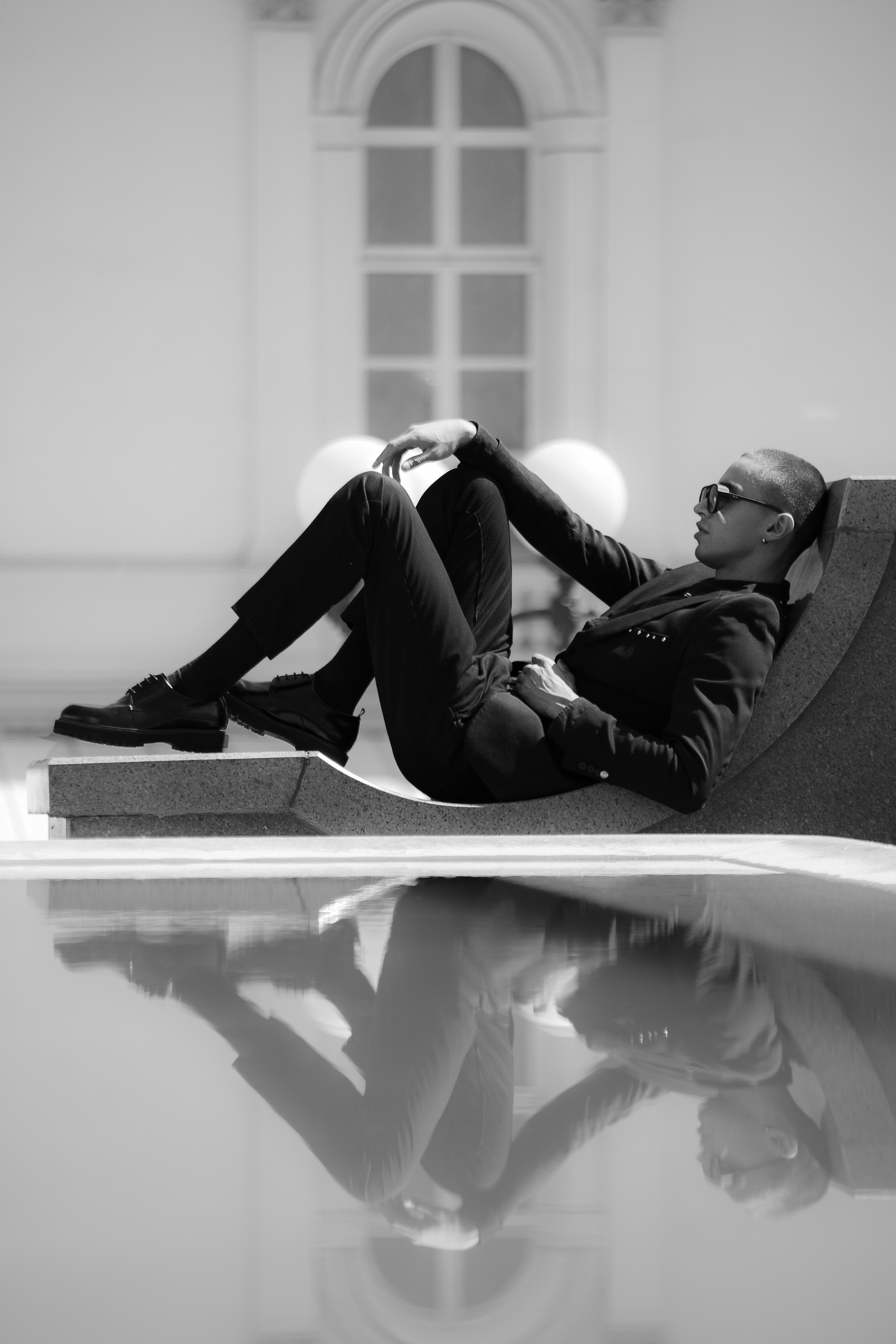 Мужчина в строгом черном костюме на фоне здания