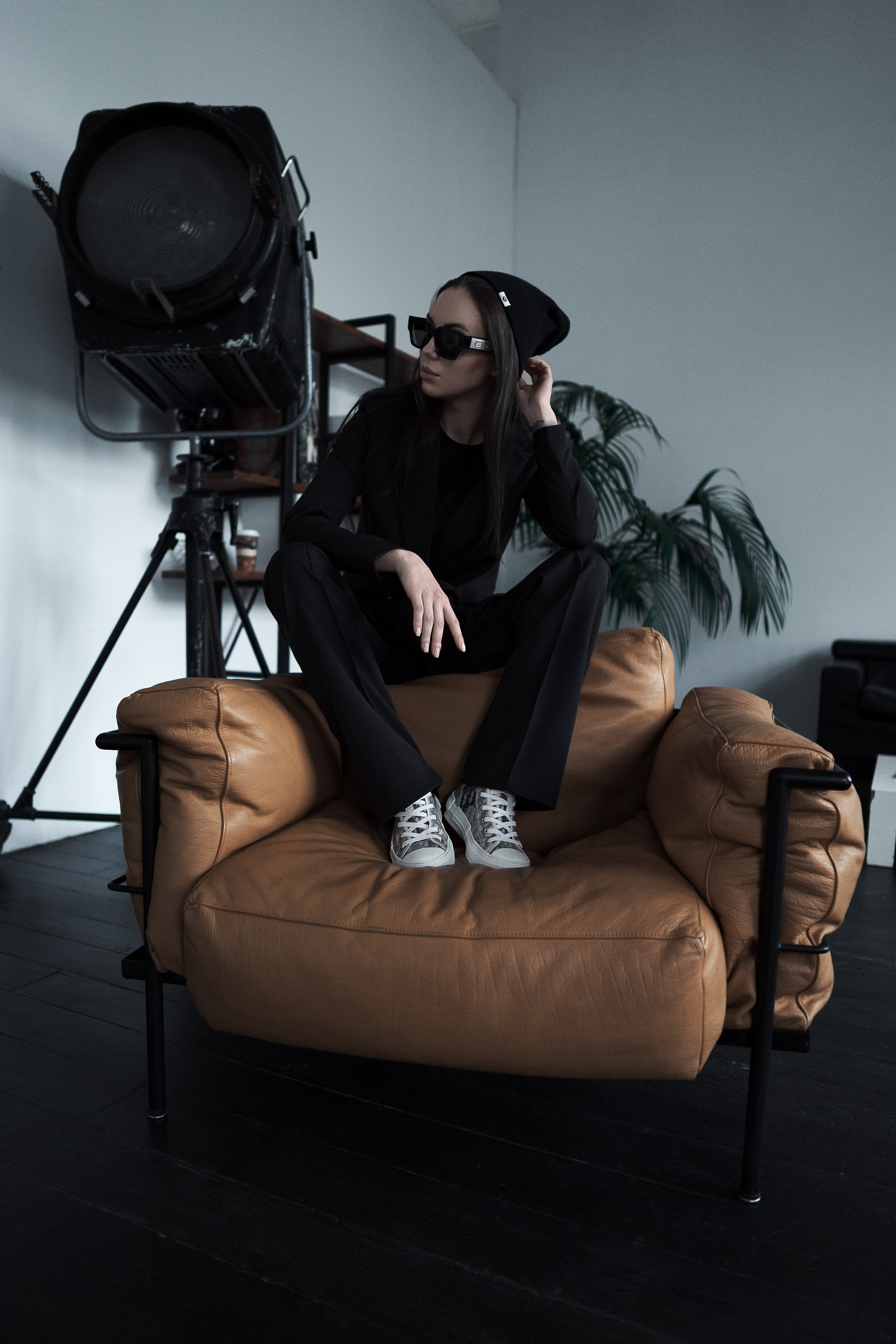 Девушка в очках и строгом костюме сидит в кресле с камерой в руках