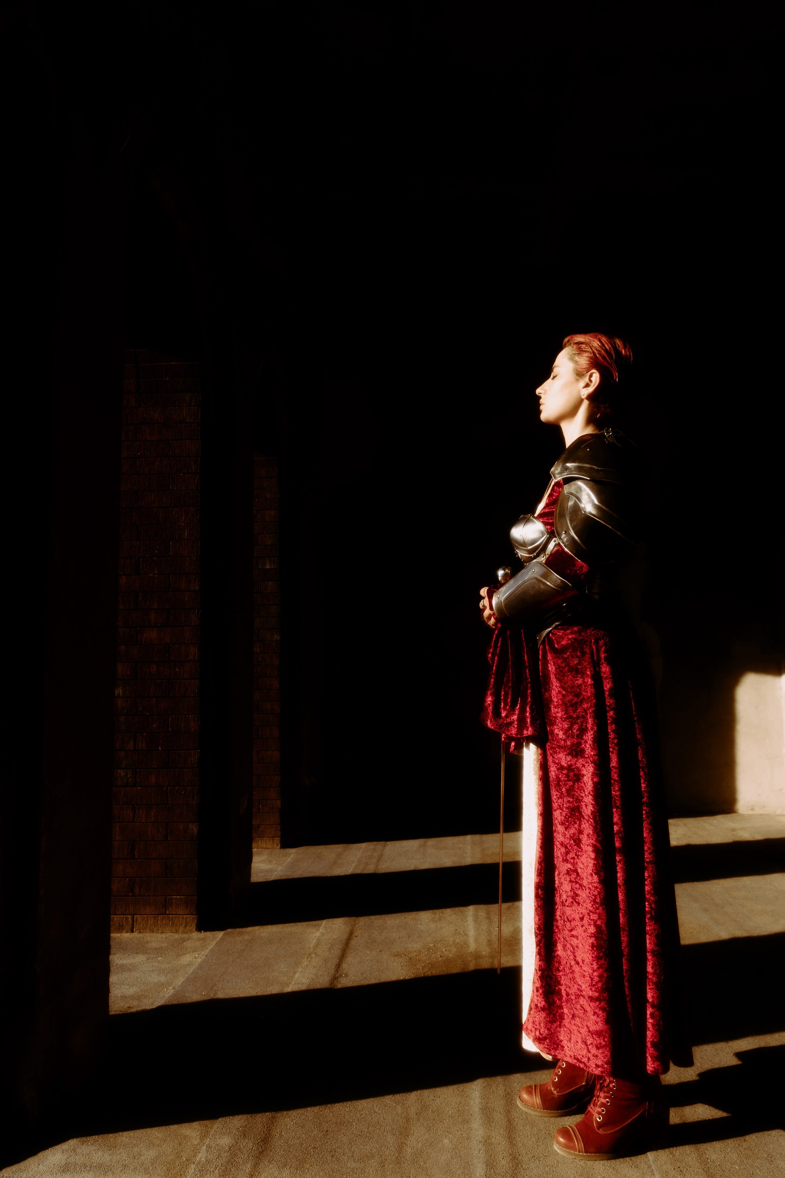 Девушка в полный рост стоит, смотря на вечерние лучи закатного солнца