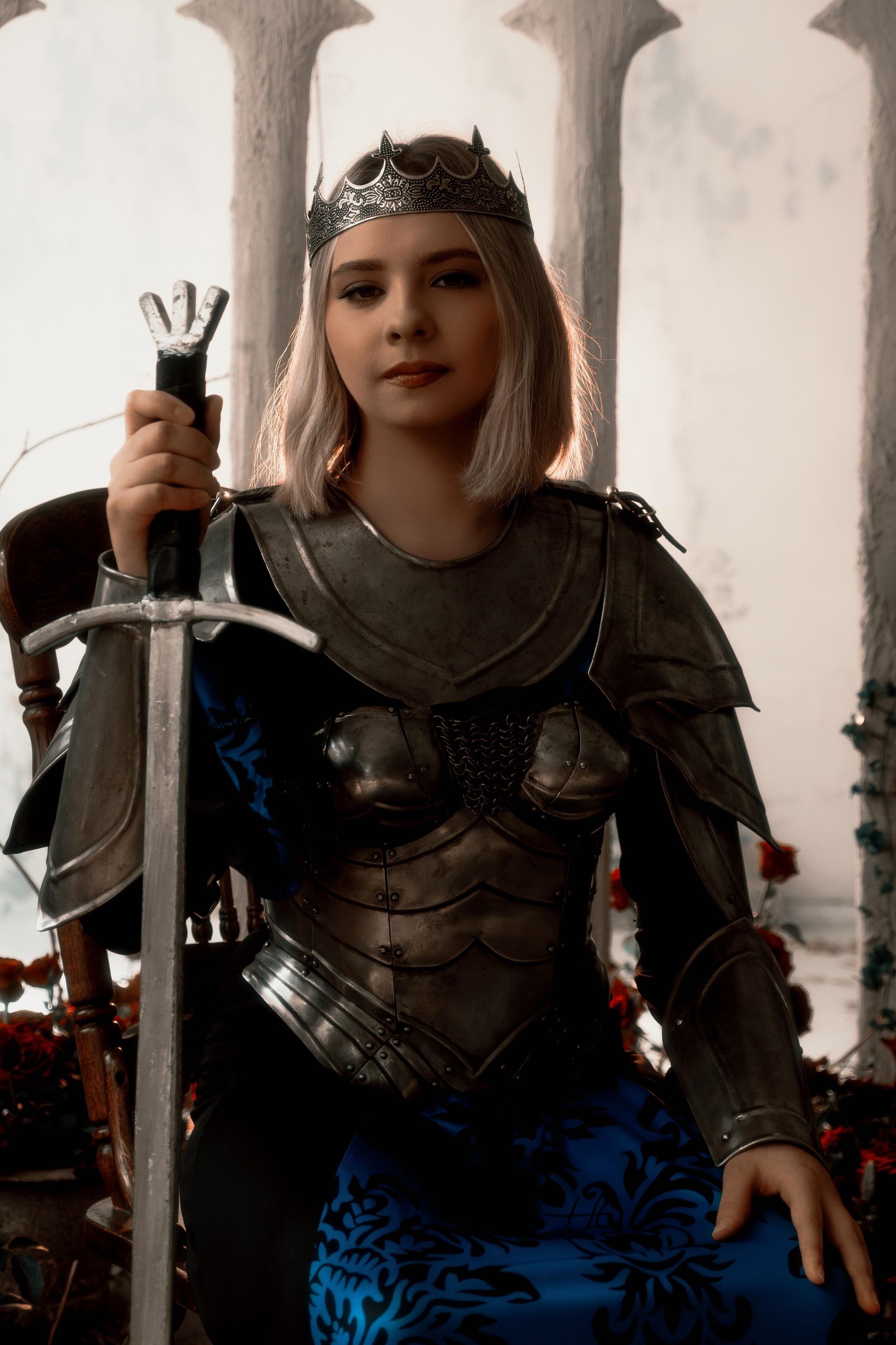 Эффектный портрет прекрасной воительницы в блестящих доспехах на фоне студийного задника. Драматическая композиция подчеркивает силу и красоту девушки-рыцаря.