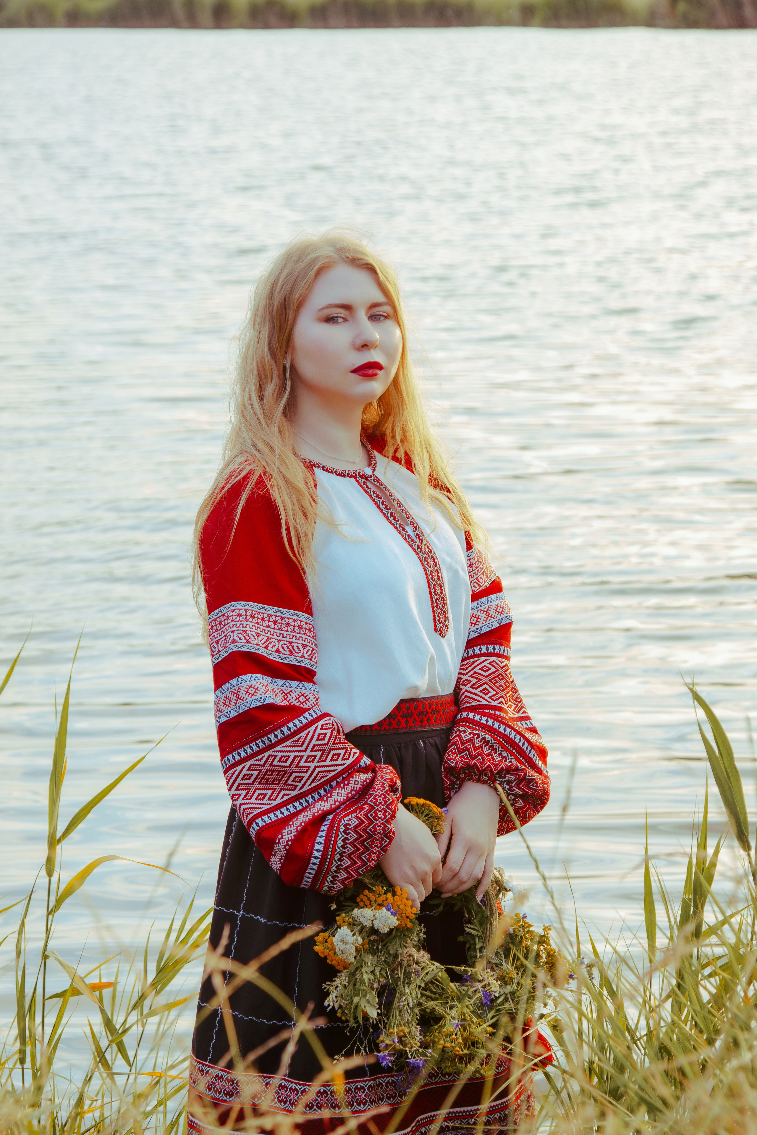 портрет славянской девушки в народной русской одежде на фоне реки в лесу