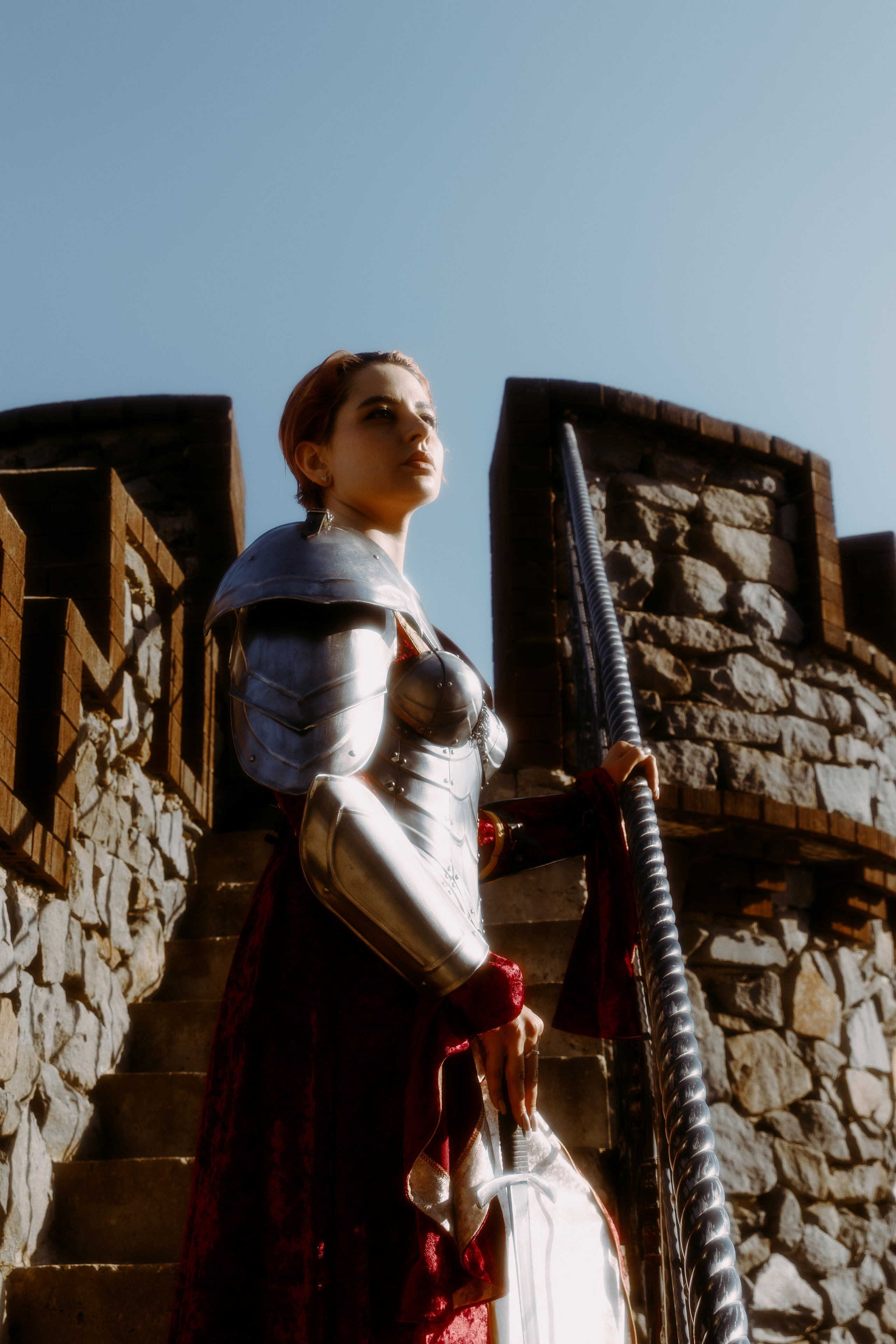 Девушка с красными волосами смотрит в даль, находясь на крыше рыцарского замка