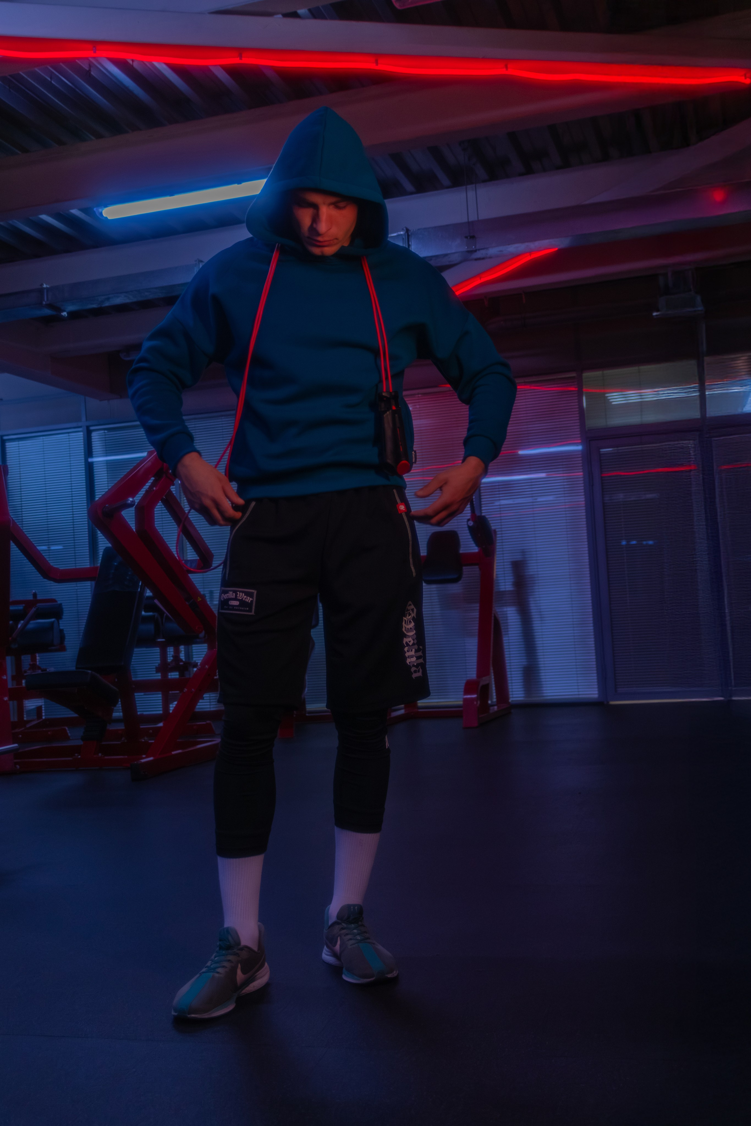 Стильный снимок мускулистого инструктора, где неоновая подсветка создает эффектный контраст с телом.