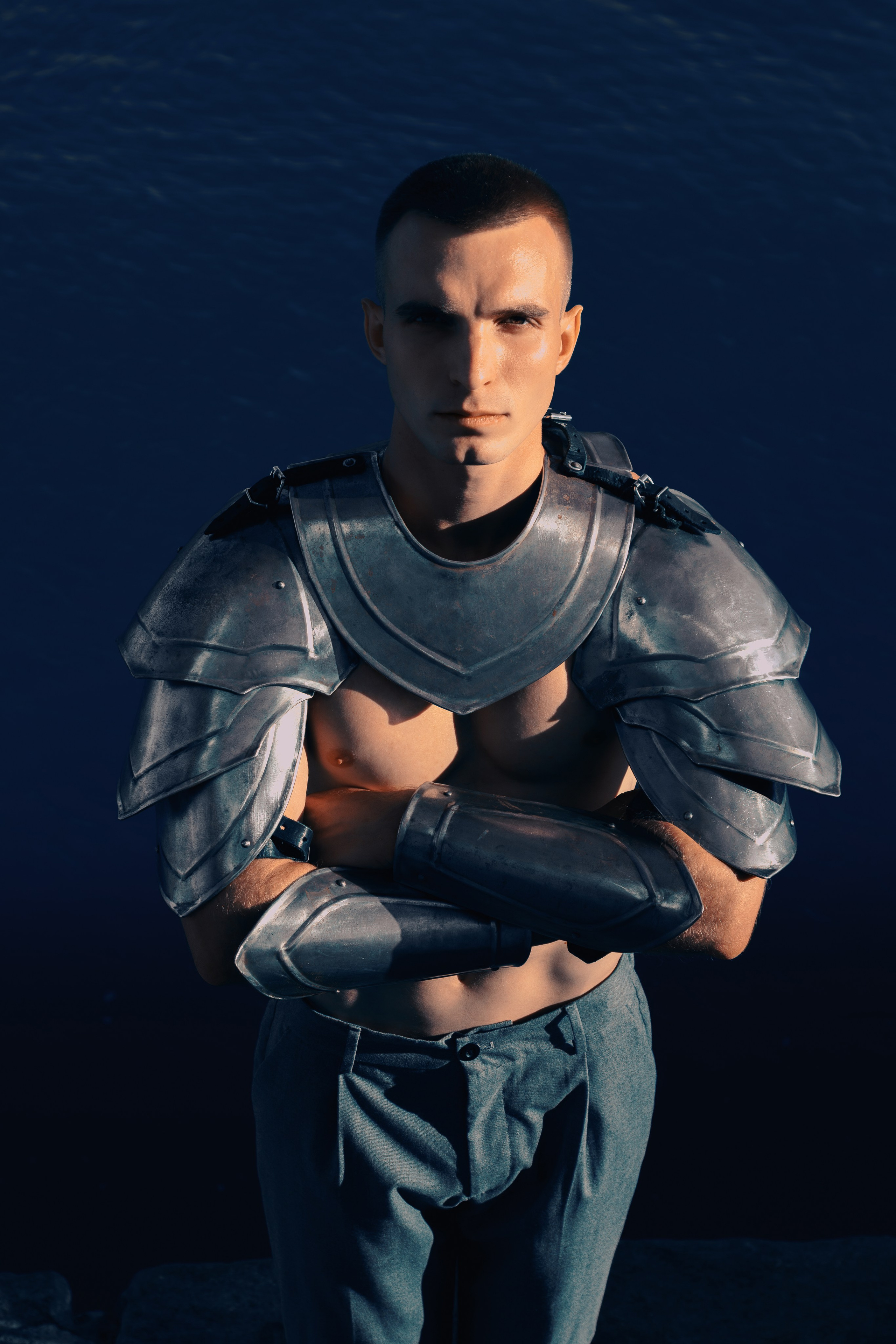 Рыцарские доспехи крупным планом. У мужчины сложены руки на груди