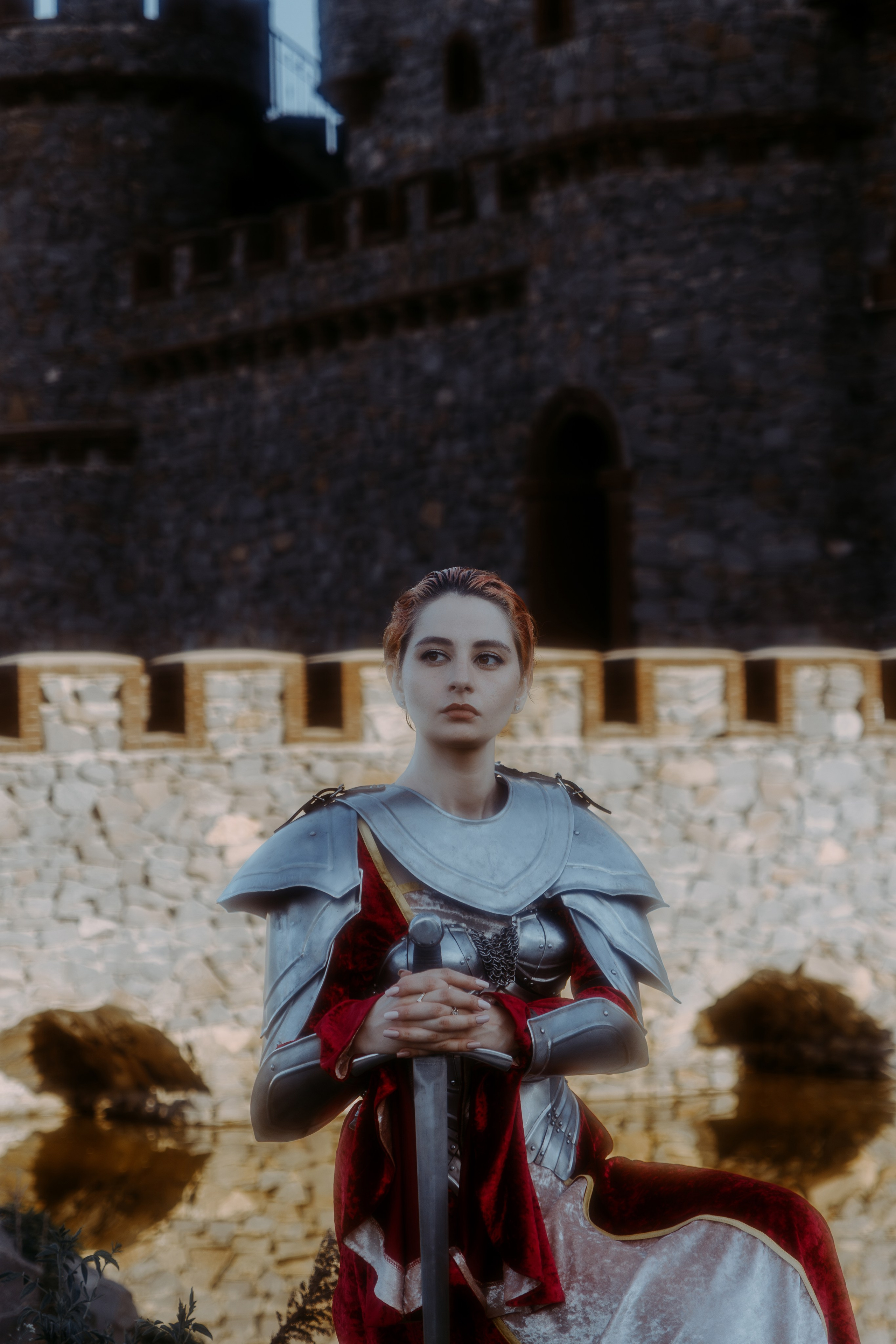 Девушка в рыцарских доспехах сиди возле замка