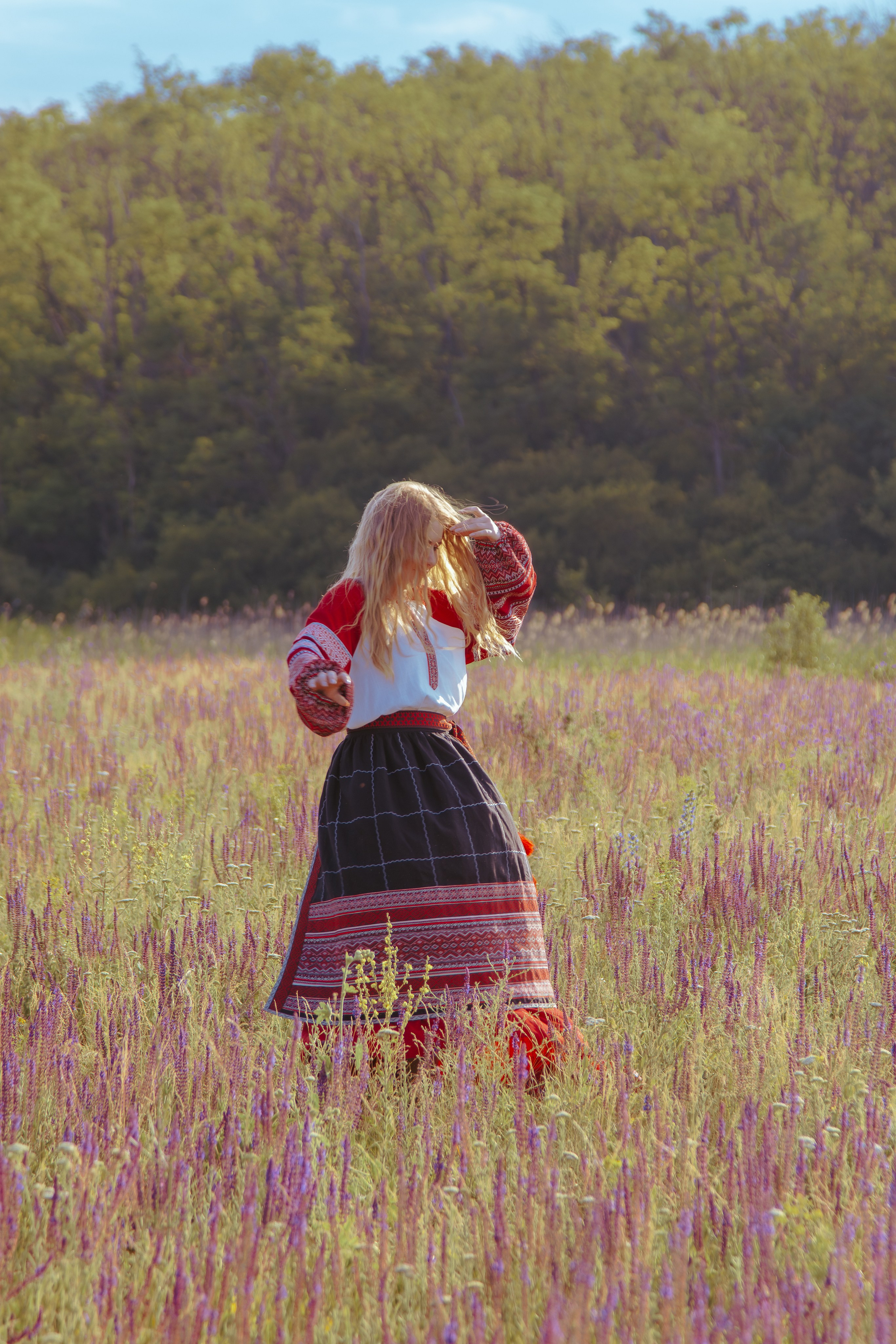 Девушка в славянской одежде позирует в поле