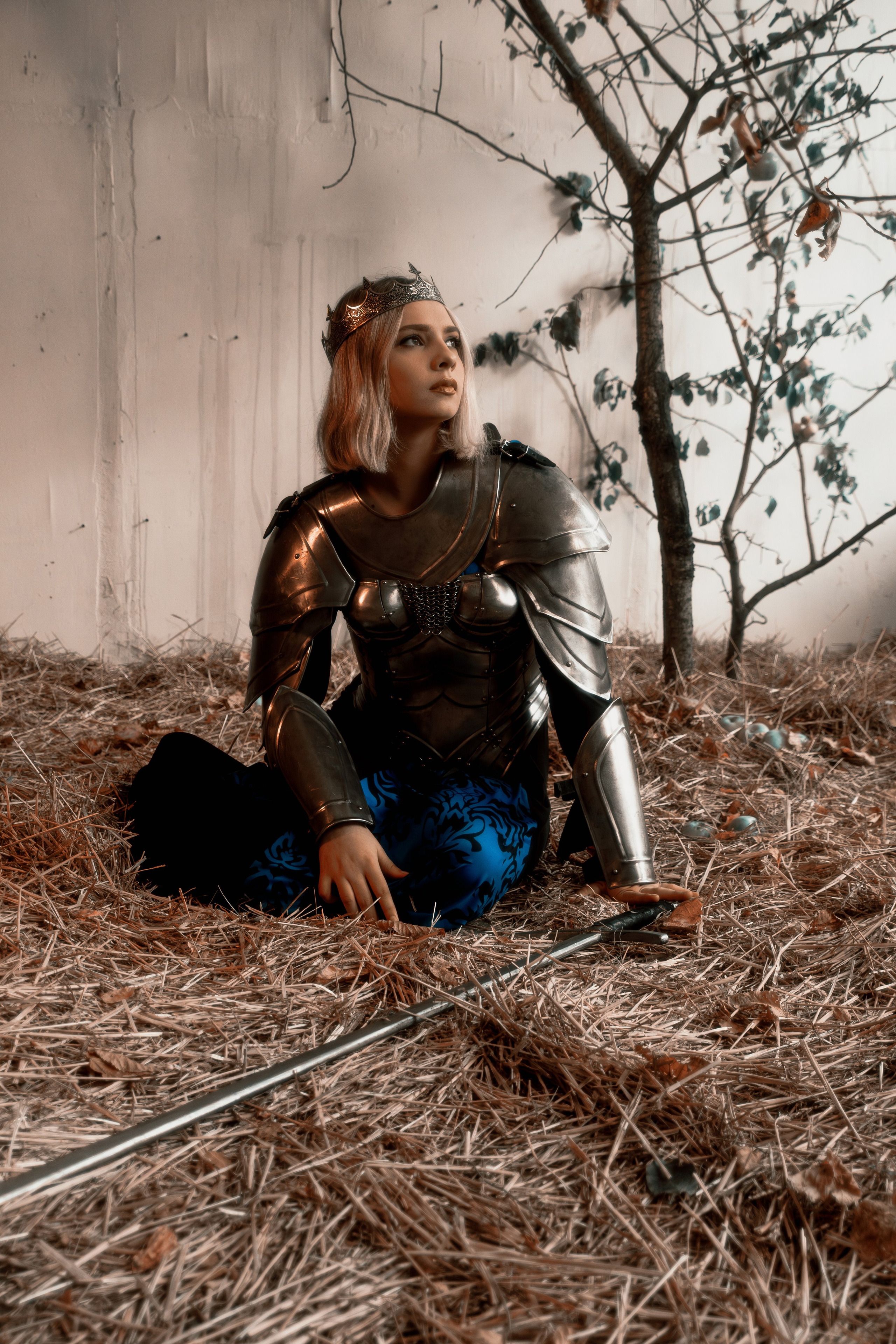 Драматичный кадр прекрасной воительницы в тяжелых доспехах на студийном фоне. Напряженная поза модели добавляет динамики снимку.