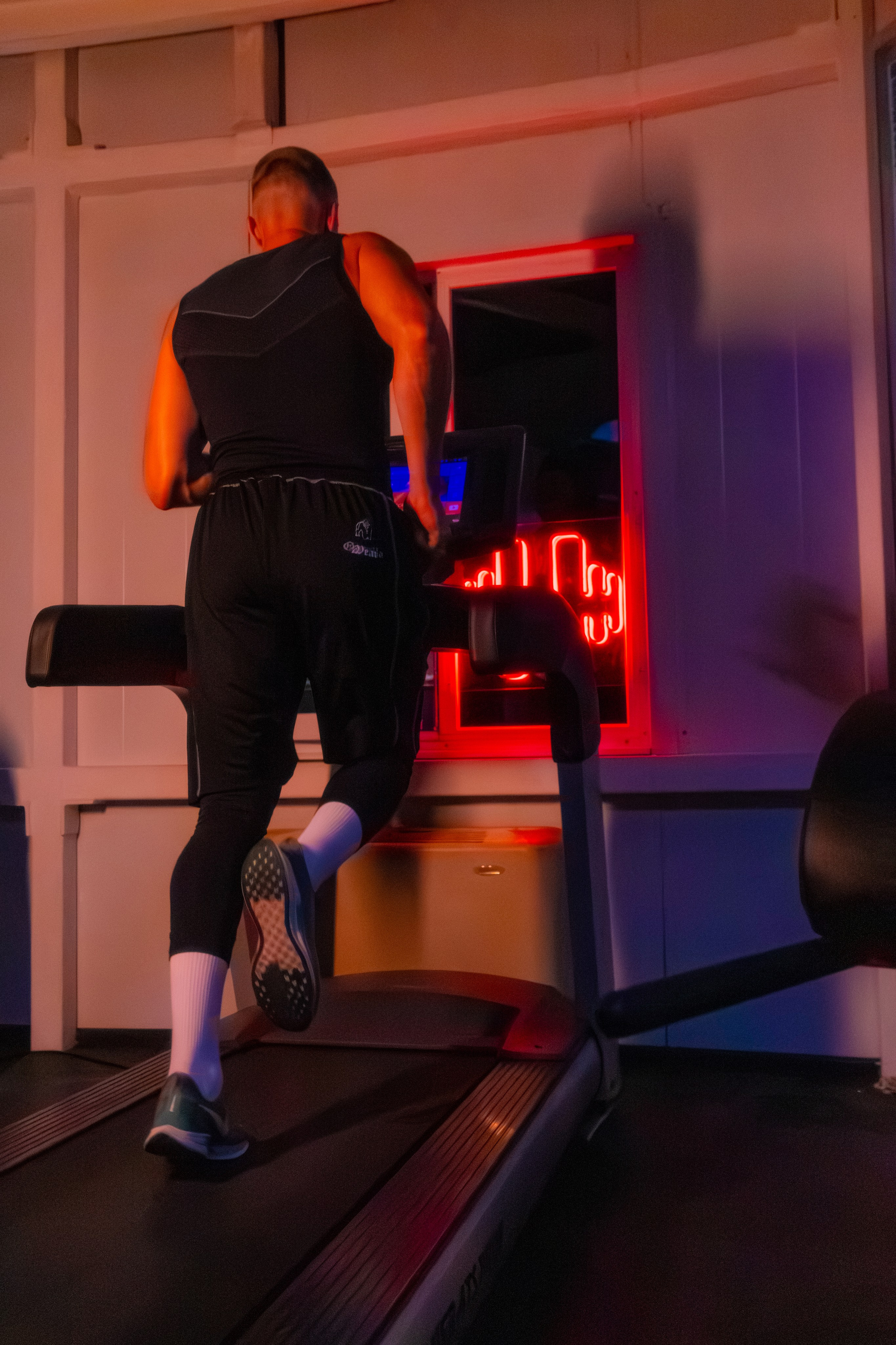 Журнальный портрет фитнес-профессионала, где цветной свет создает драматический эффект.