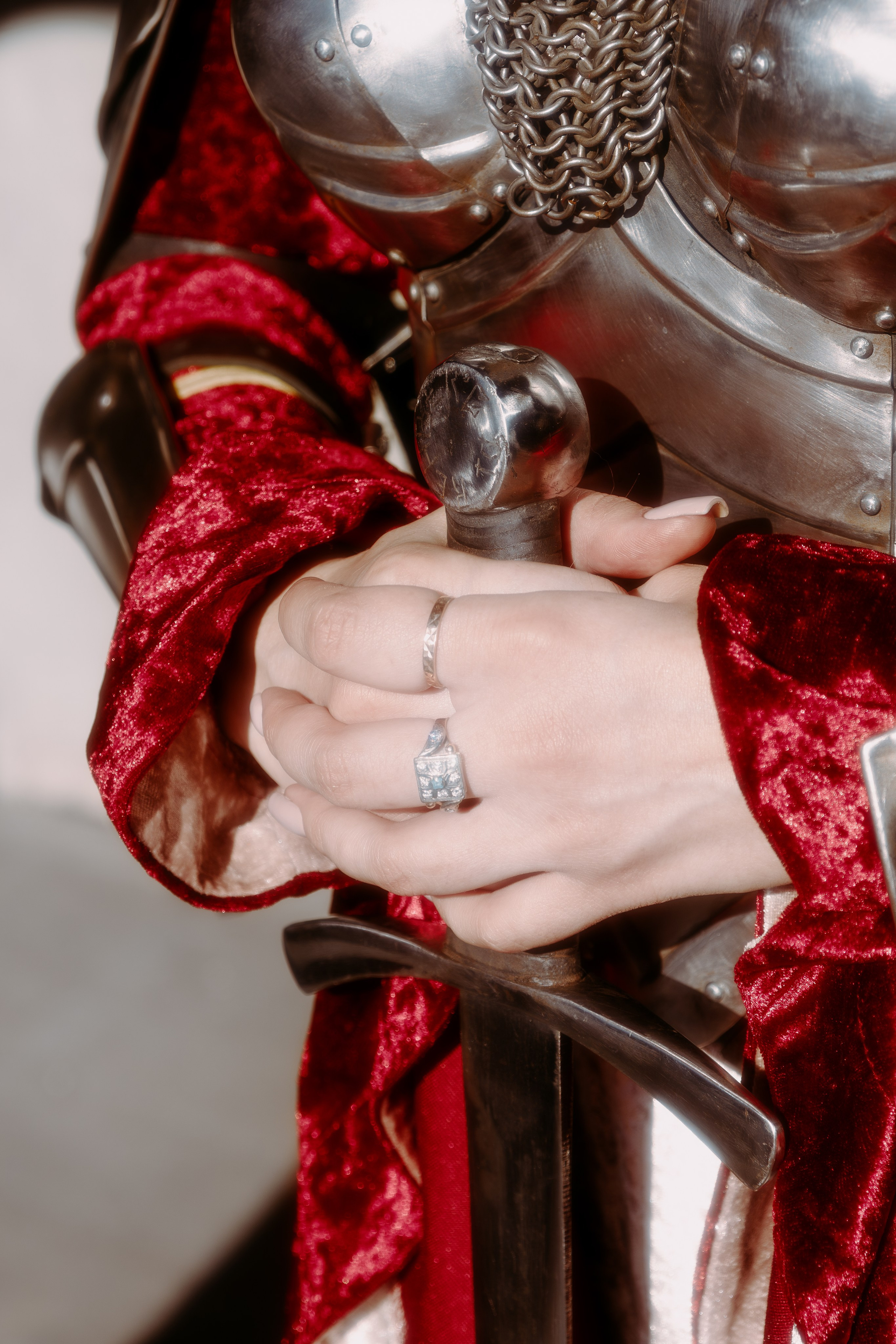 Детали на фото: прекрасное кольцо и красивые руки держат грубый рыцарский меч